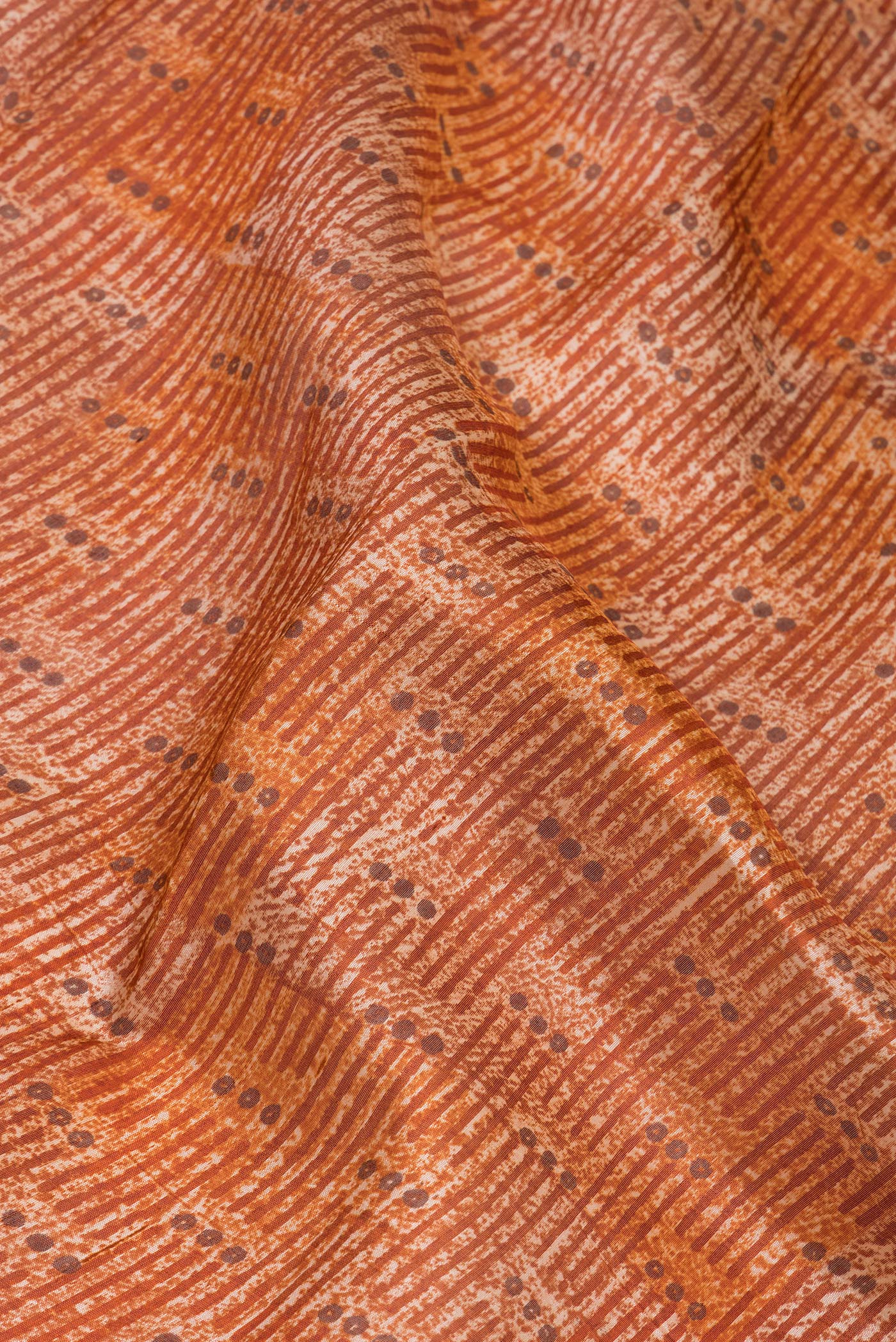 Close up of Brick Orange Tussar Silk Saree with Printed design on the body and Printed Border.  displaying folds