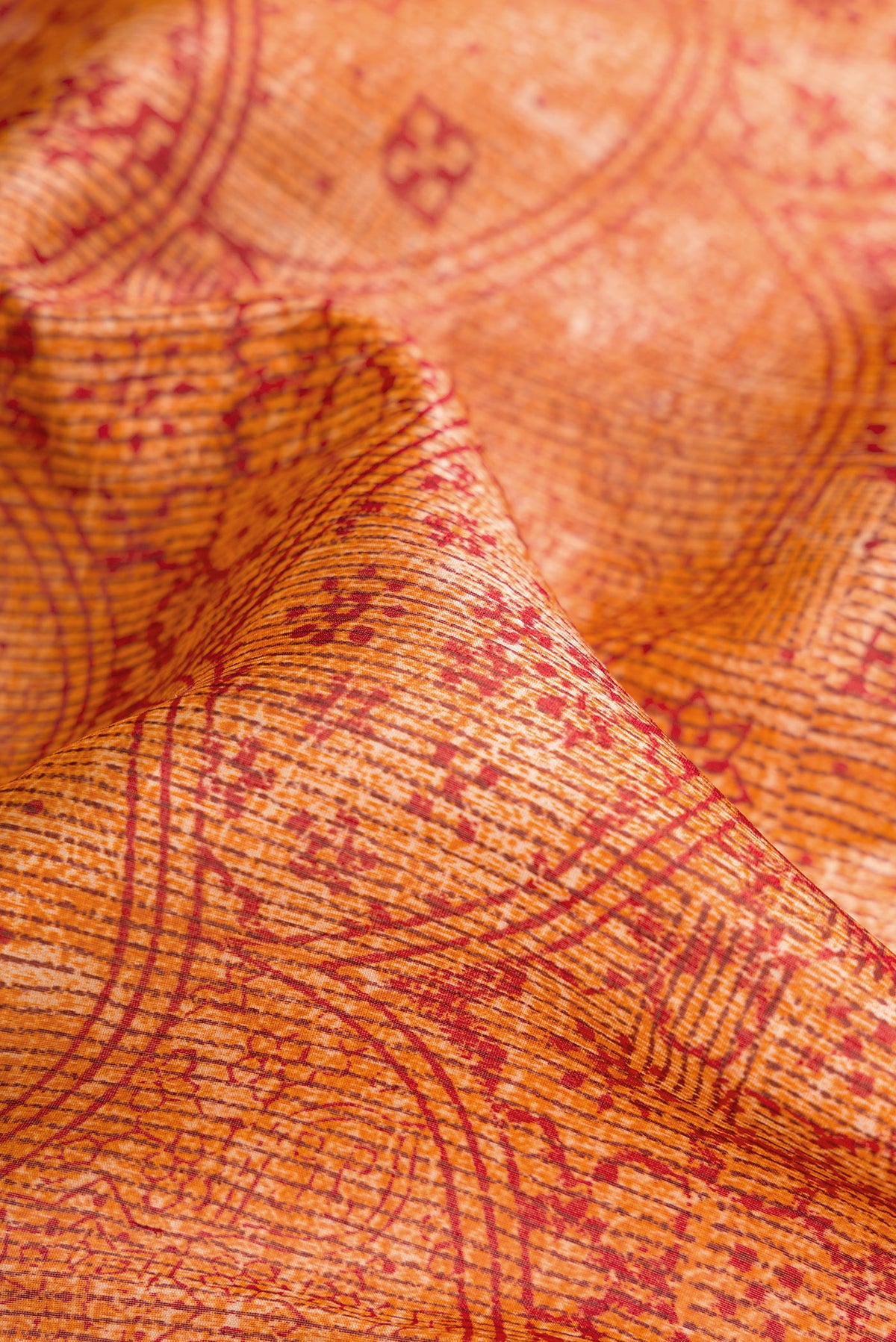 Close up of Orange Dual Tone Tussar Silk Saree with Printed design on the body and Printed Border.  displaying folds
