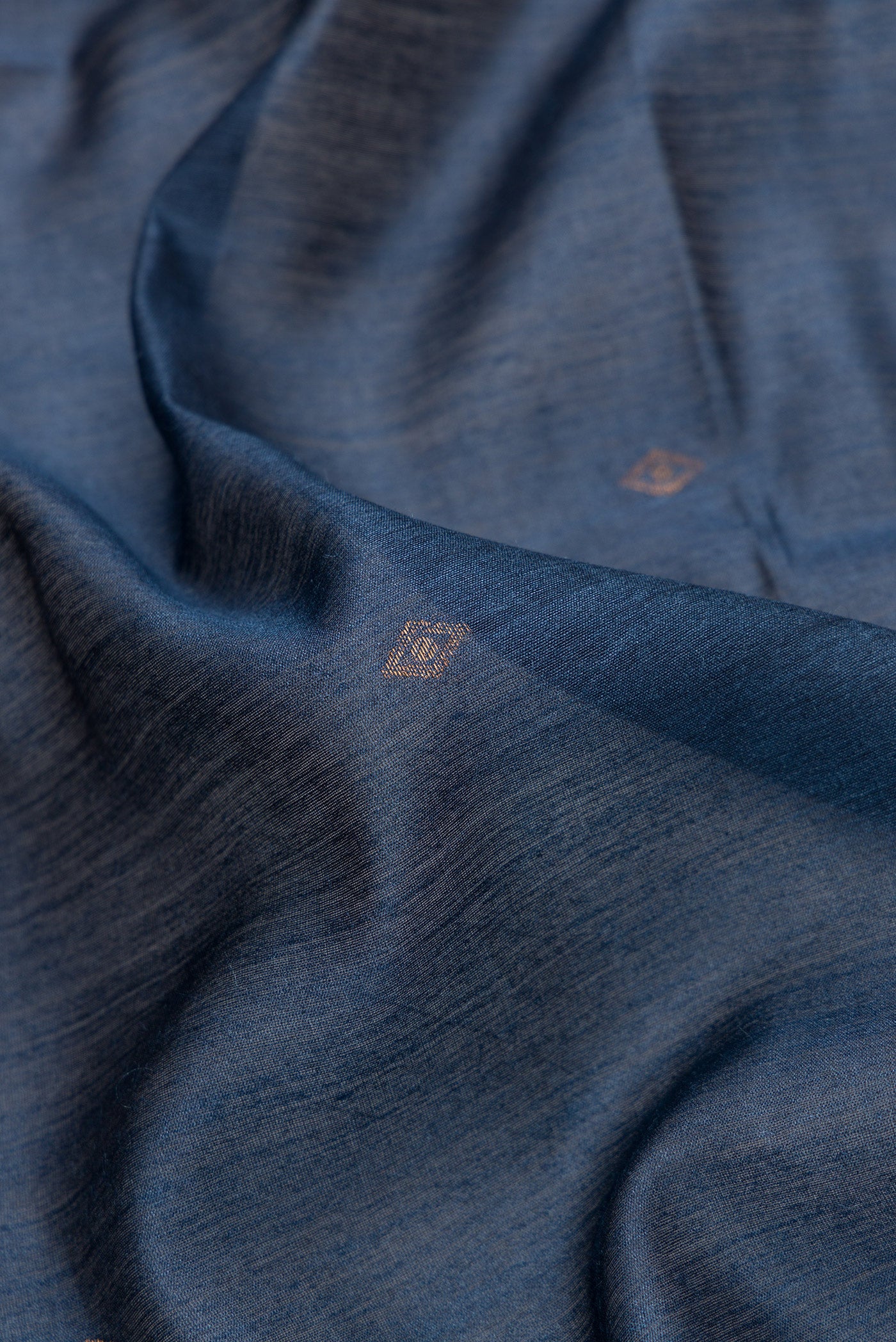 Close up of Navy Blue Dual Tone Tussar Silk Saree with Zari Butta on the body and Ikat Border.  displaying folds
