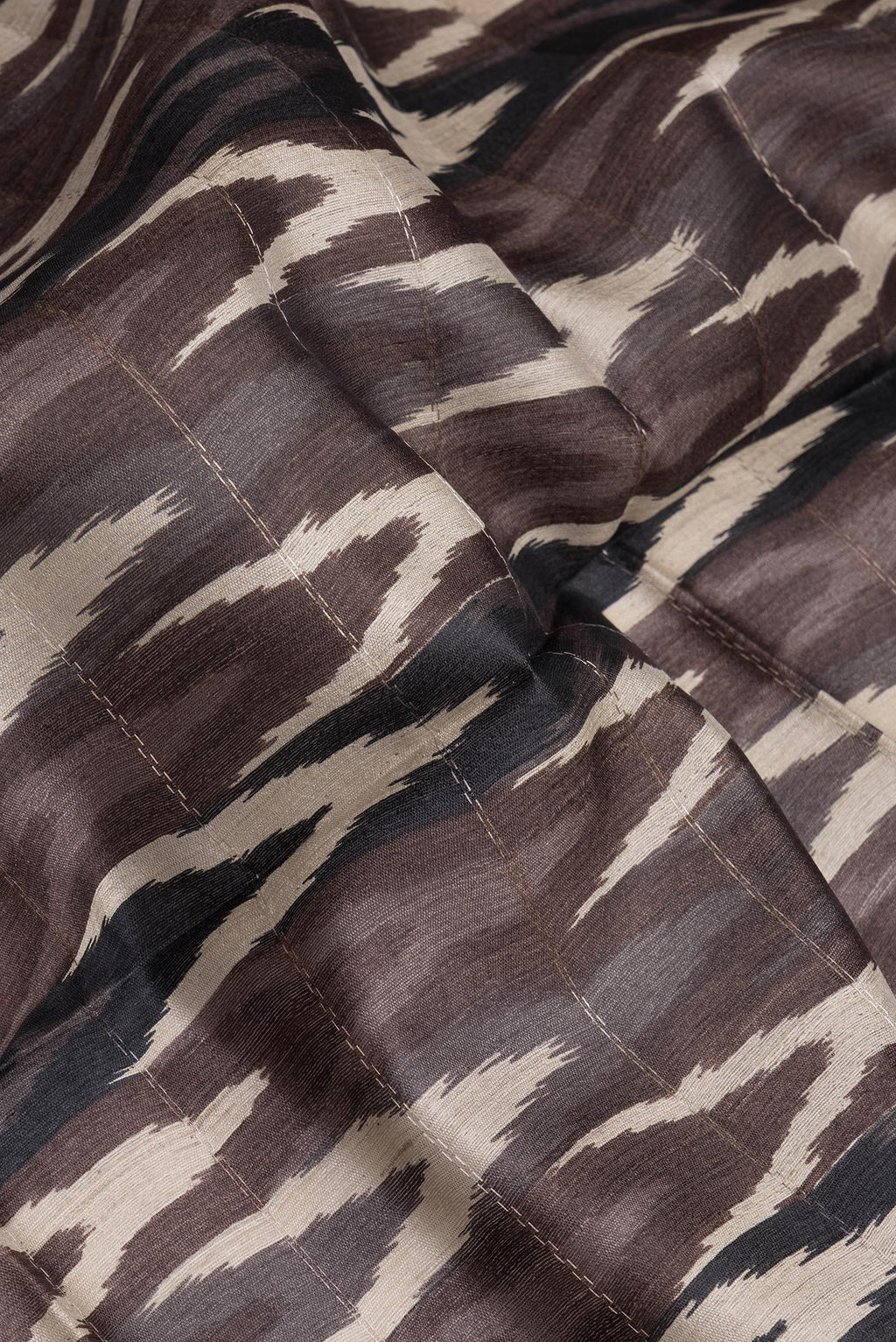 Close up of Brown Tussar Silk Saree with Ikat Print on the body and Zari Border.  displaying folds