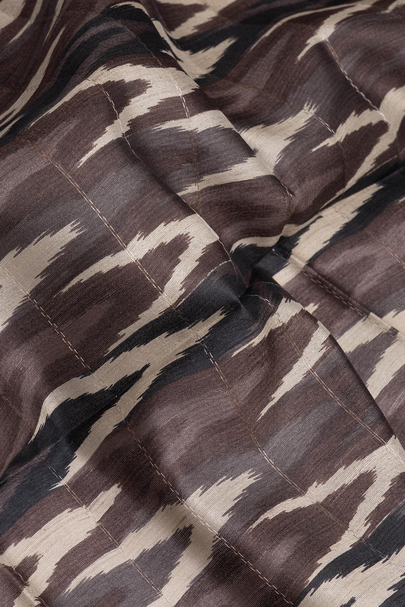 Close up of Brown Tussar Silk Saree with Ikat Print on the body and Zari Border.  displaying folds