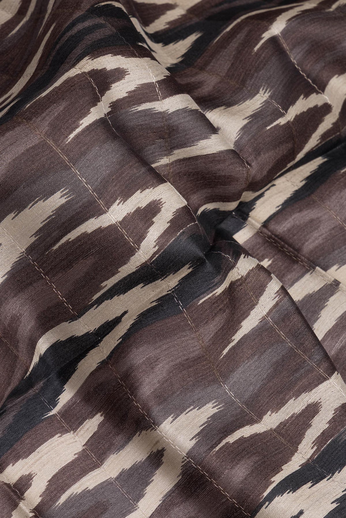 Close up of Brown Tussar Silk Saree with Ikat Print on the body and Zari Border.  displaying folds