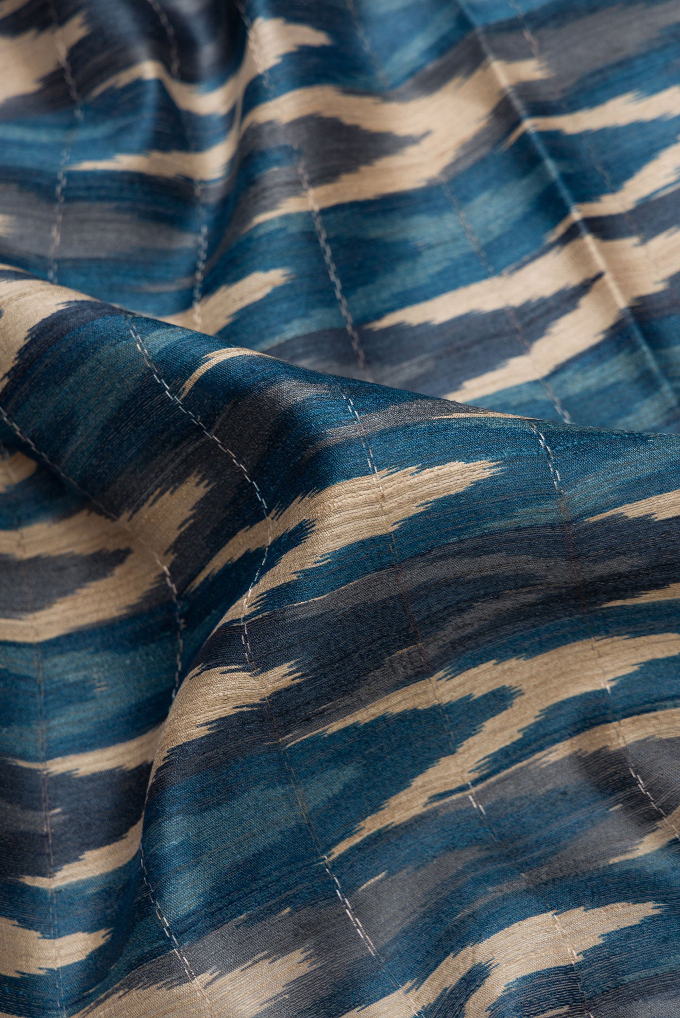 Close up of Peacock Blue and Beige Color Tussar Silk Saree with Ikat Print on the body and Zari Border.  displaying folds