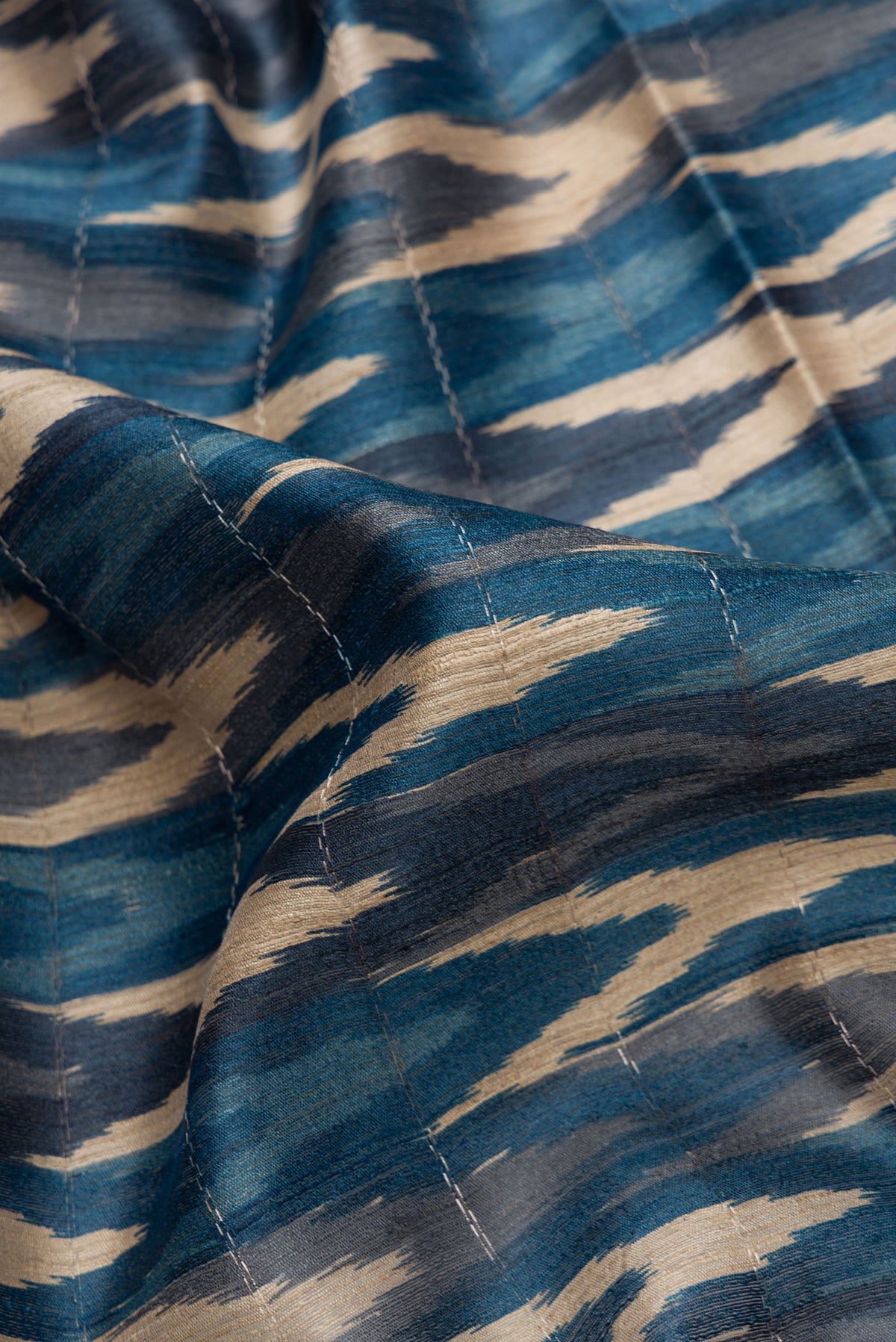 Close up of Peacock Blue and Beige Color Tussar Silk Saree with Ikat Print on the body and Zari Border.  displaying folds