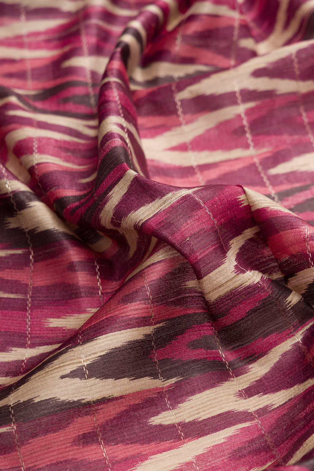 Close up of Pink and Off White Color Tussar Silk Saree with Ikat Print on the body and Zari Border.  displaying folds