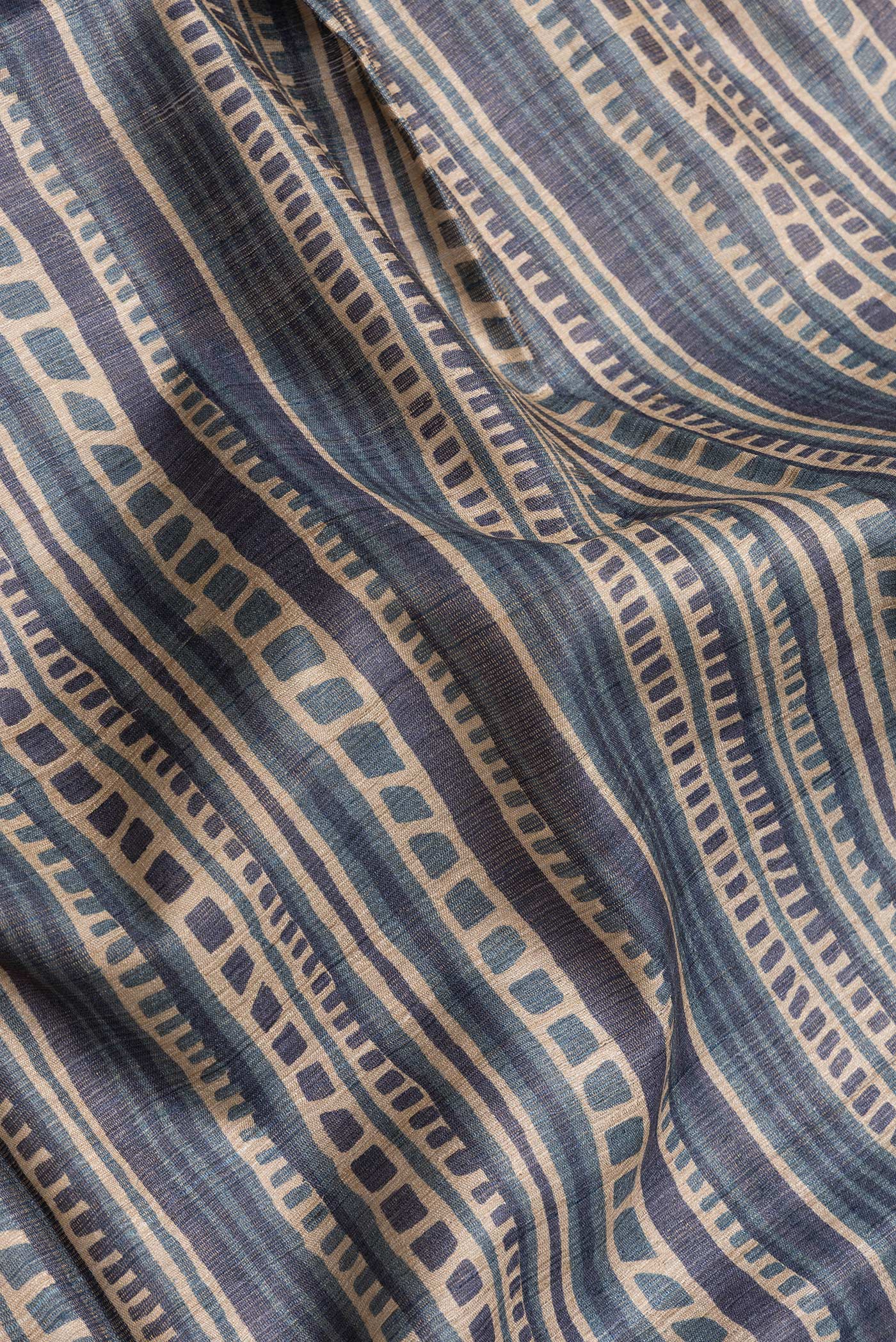 Close up of Beige Dual Tone Tussar Silk Saree with Printed design on the body and Printed Border.  displaying folds