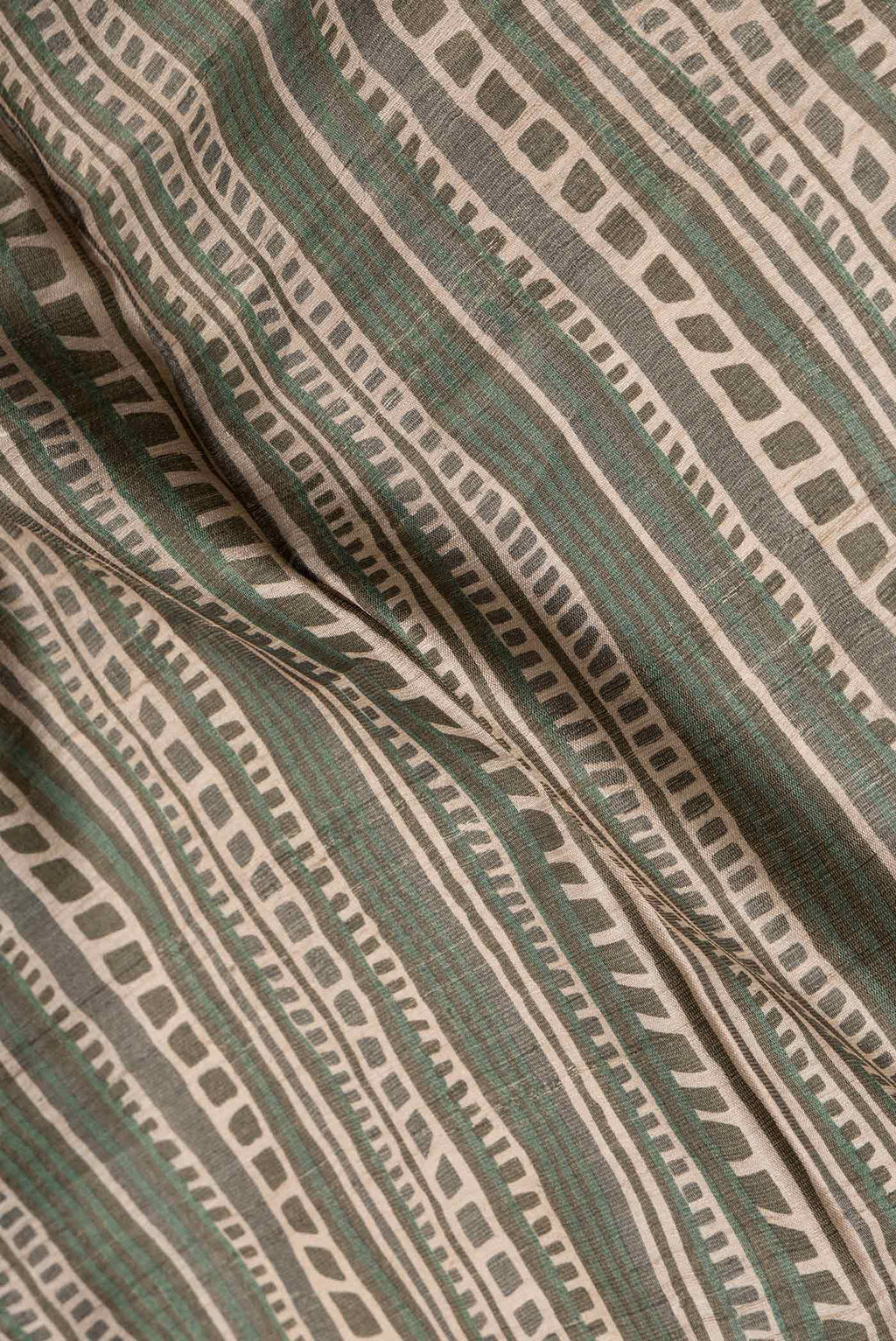 Close up of Green Dual Tone Tussar Silk Saree with Printed design on the body and Fancy Border.  displaying folds