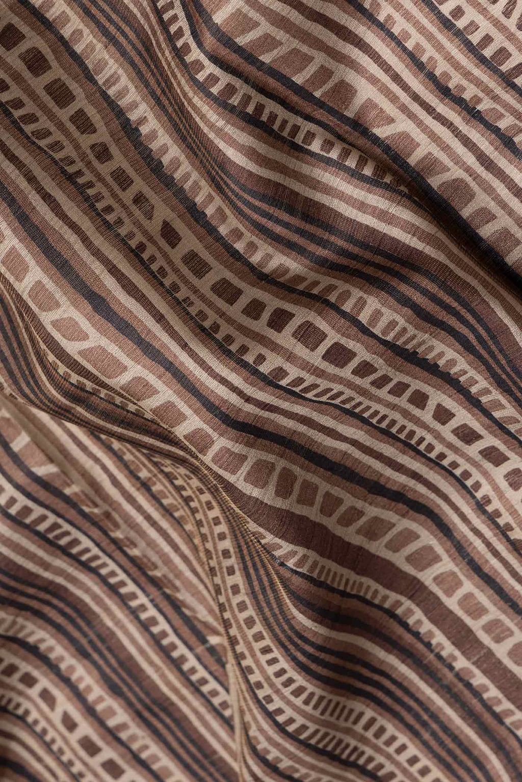 Close up of Brown Dual Tone Tussar Silk Saree with Printed design on the body and Fancy Border.  displaying folds