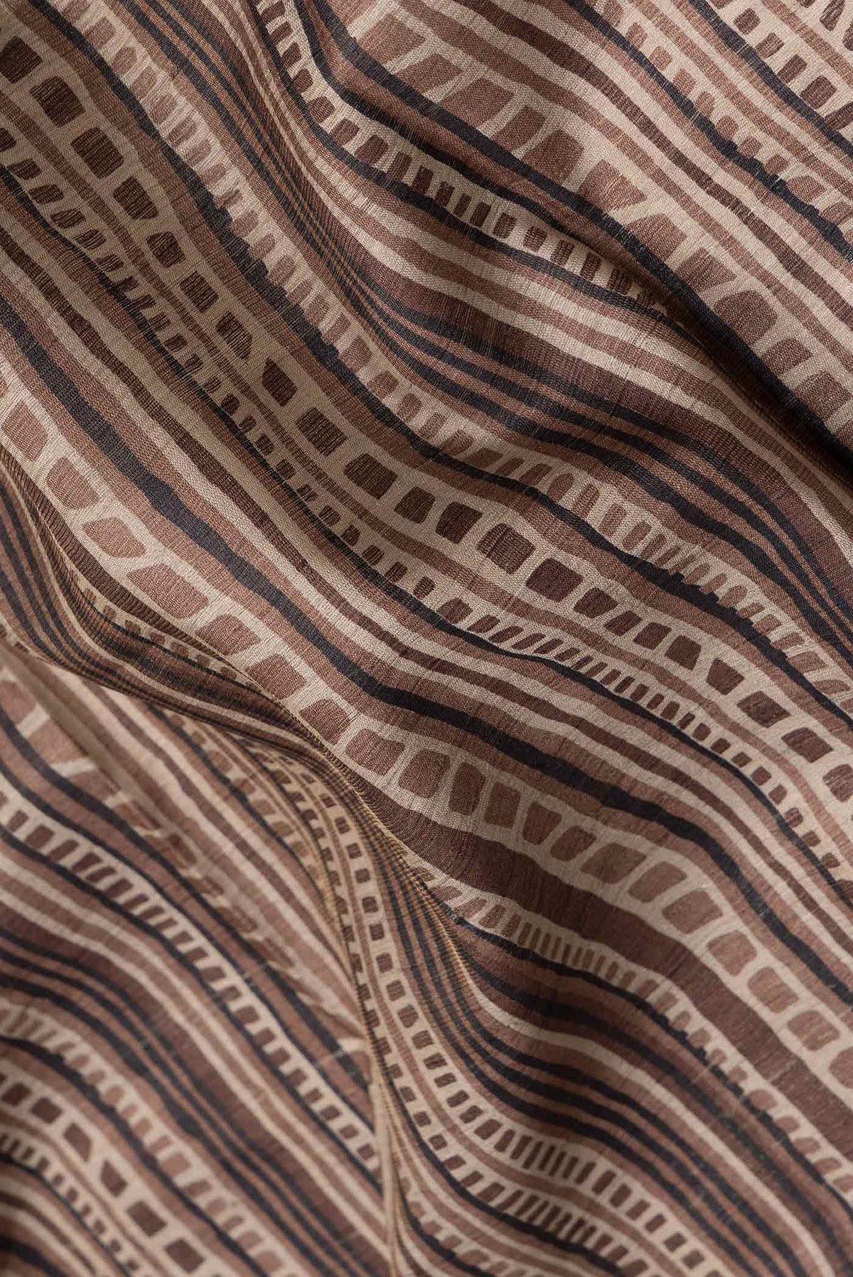 Close up of Brown Dual Tone Tussar Silk Saree with Printed design on the body and Fancy Border.  displaying folds