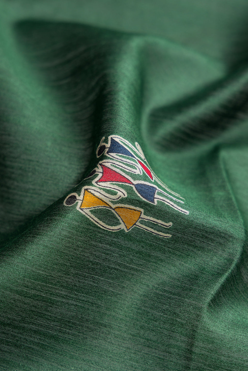 Close up of Green Dual Tone Tussar Silk Saree with Printed design on the body and Ikat Border.  displaying folds