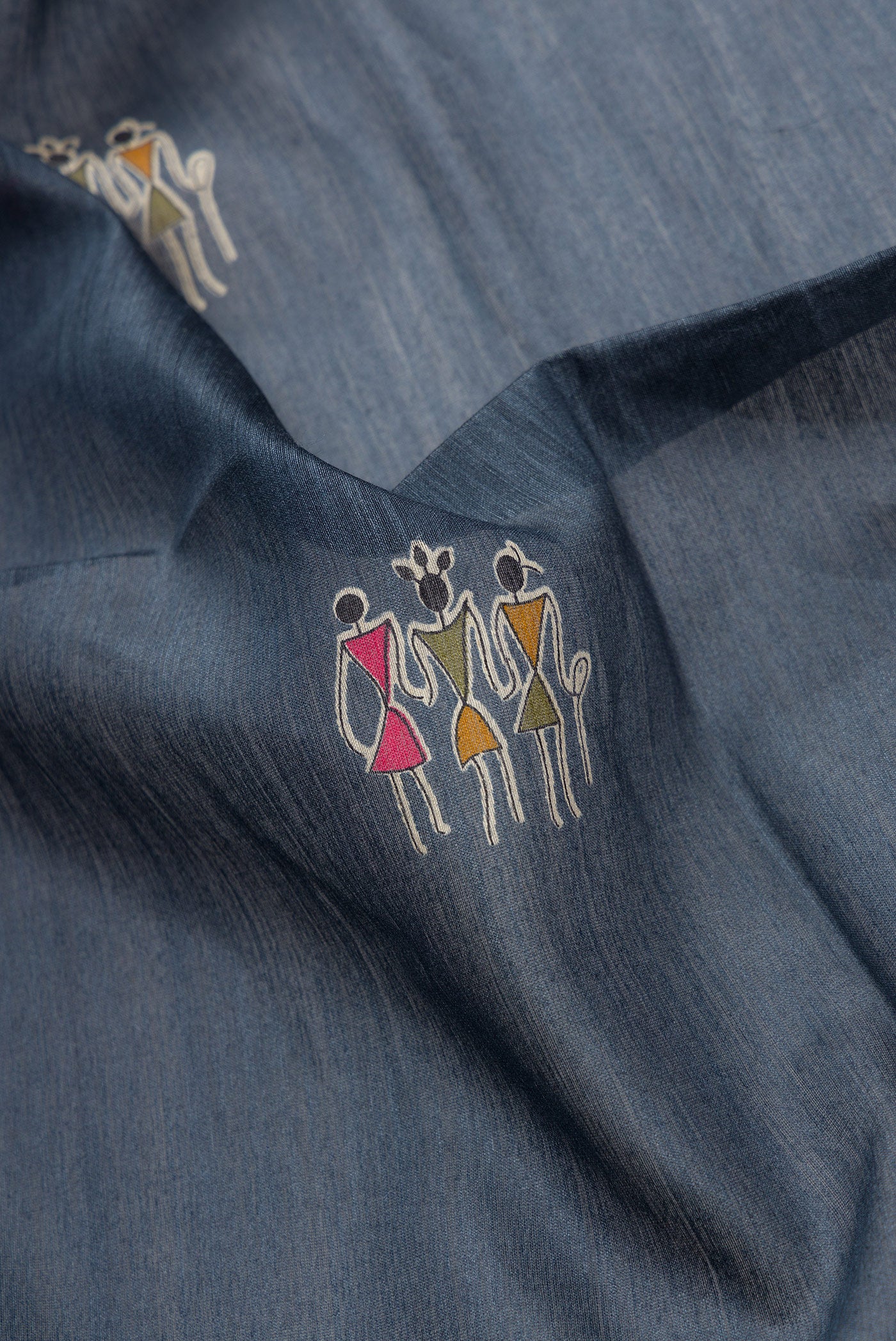 Close up of Grey Dual Tone Tussar Silk Saree with Printed design on the body and Ikat Border.  displaying folds