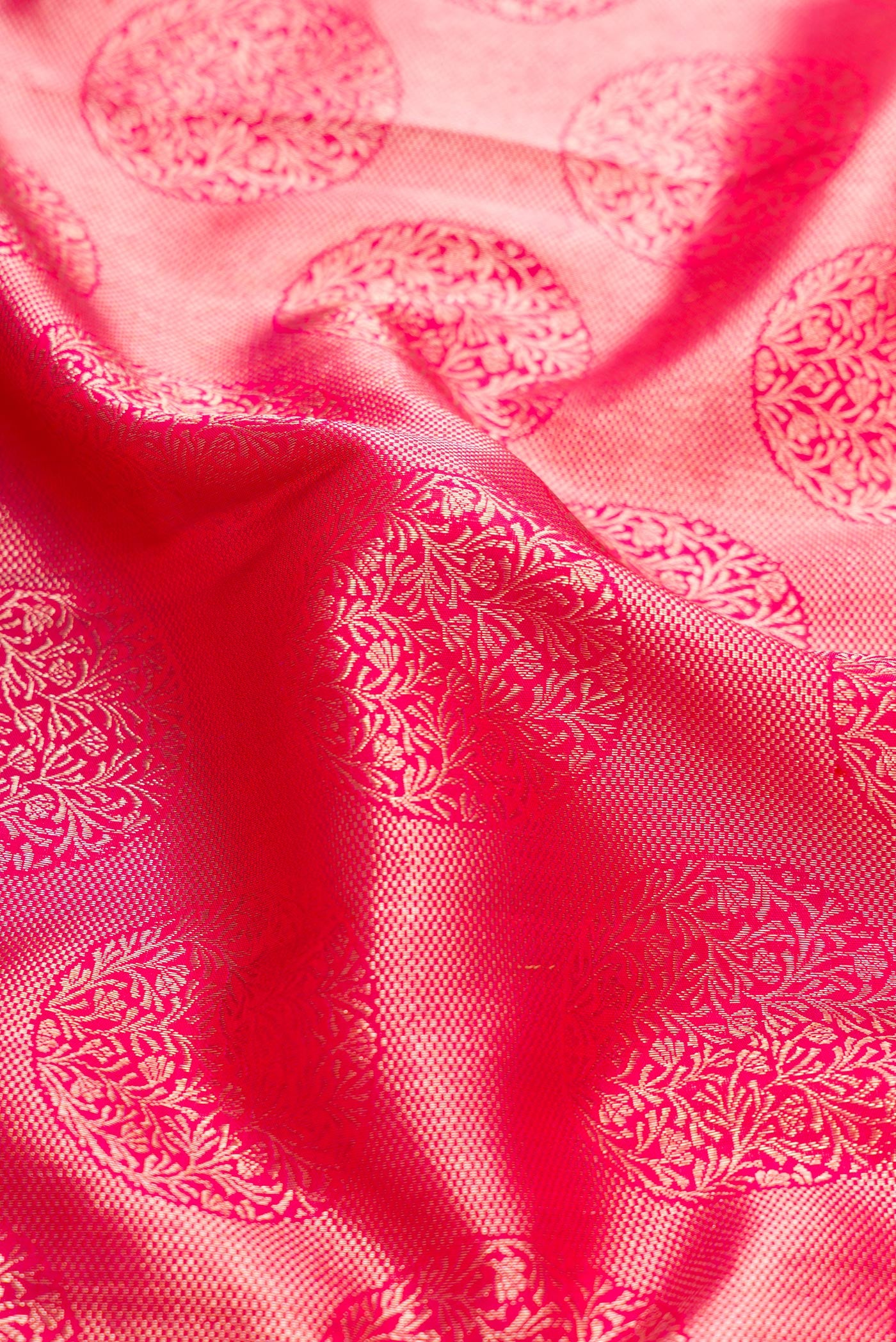 Close up of Pink Dual Tone Kanchipuram Silk Saree with Zari Butta on the body and Zari Border.  displaying folds