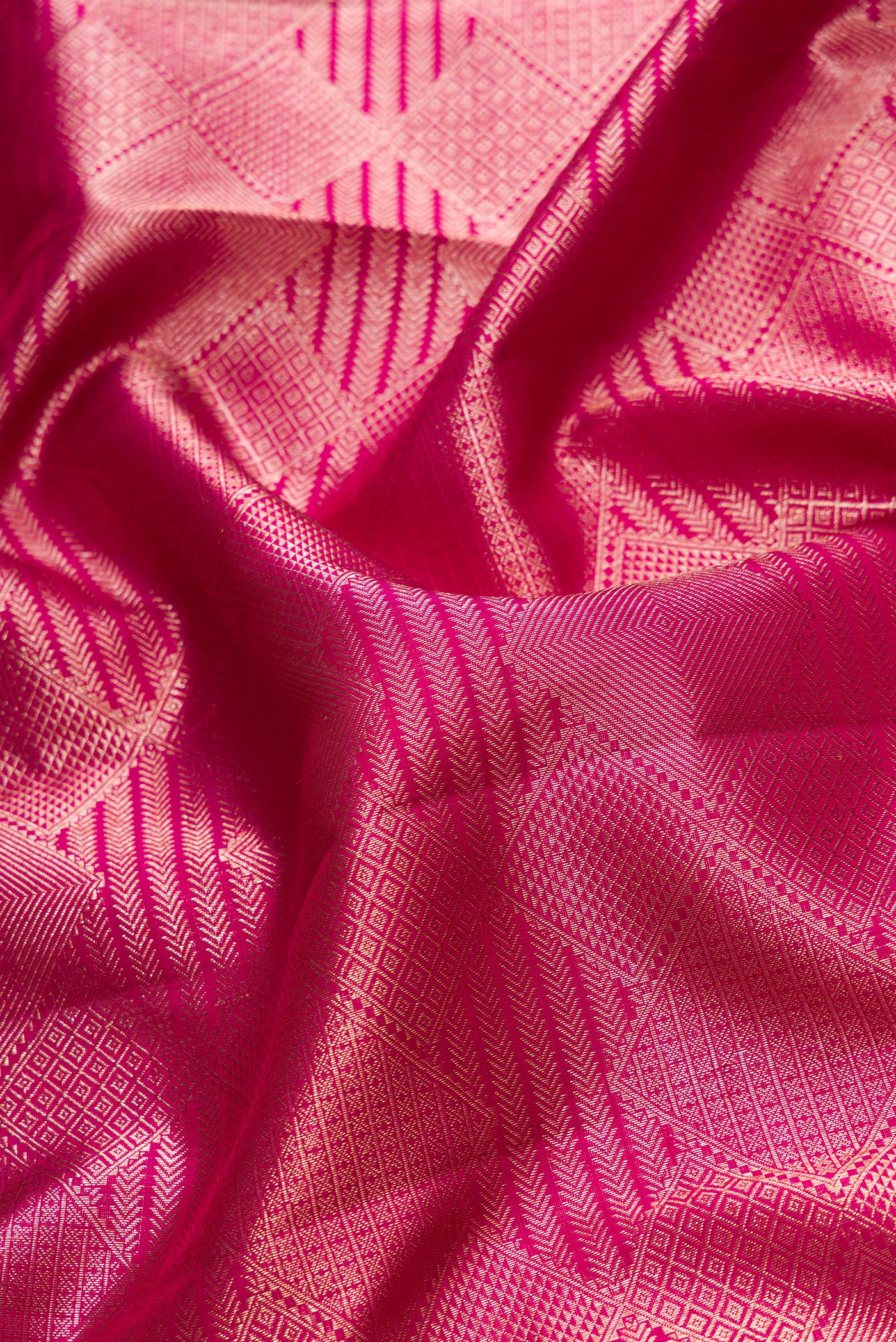Close up of Magenta Dual Tone Kanchipuram Silk Saree with Zari Brocade on the body and Zari Border.  displaying folds
