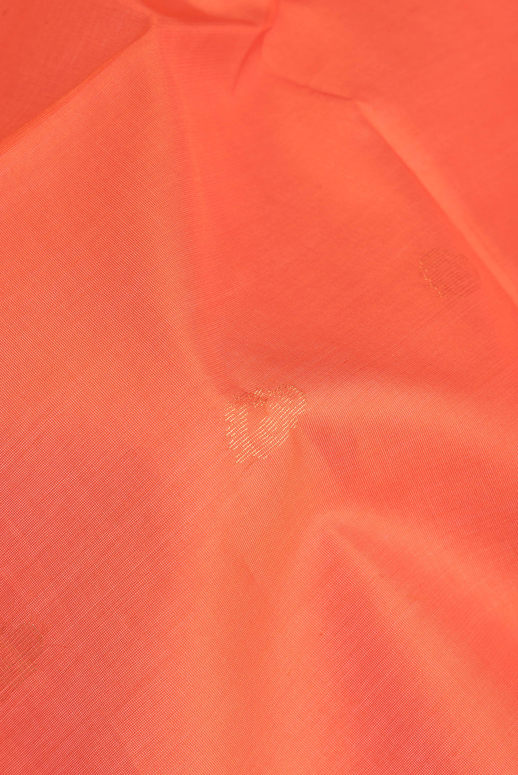 Close up of Orange Silk Cotton Saree with Zari Butta on the body and Zari Border.  displaying folds