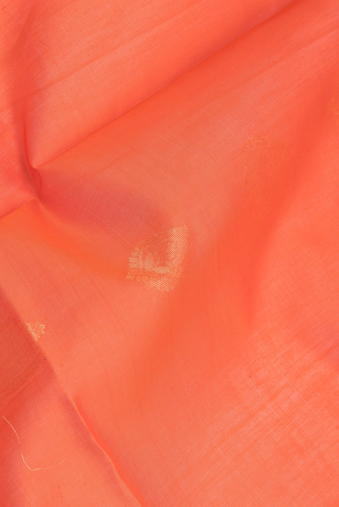 Close up of Orange Silk Cotton Saree with Zari Butta on the body and Zari Border.  displaying folds