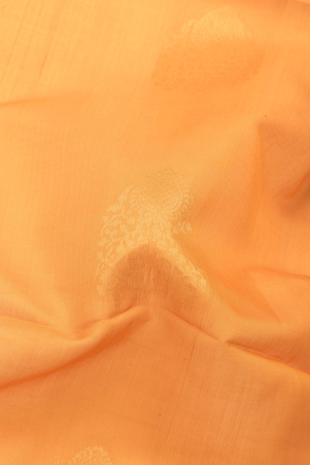 Close up of Orange Silk Cotton Saree with Zari Butta on the body and Zari Border.  displaying folds