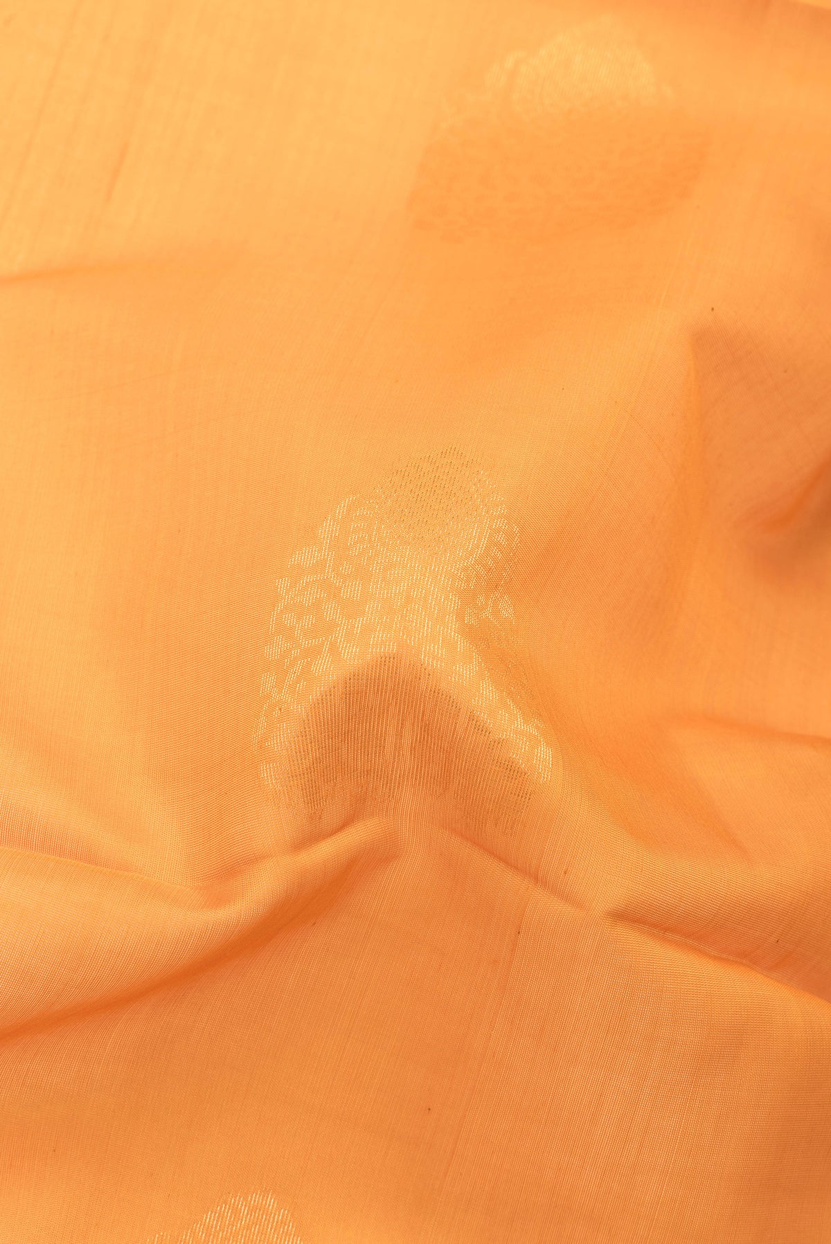 Close up of Orange Silk Cotton Saree with Zari Butta on the body and Zari Border.  displaying folds