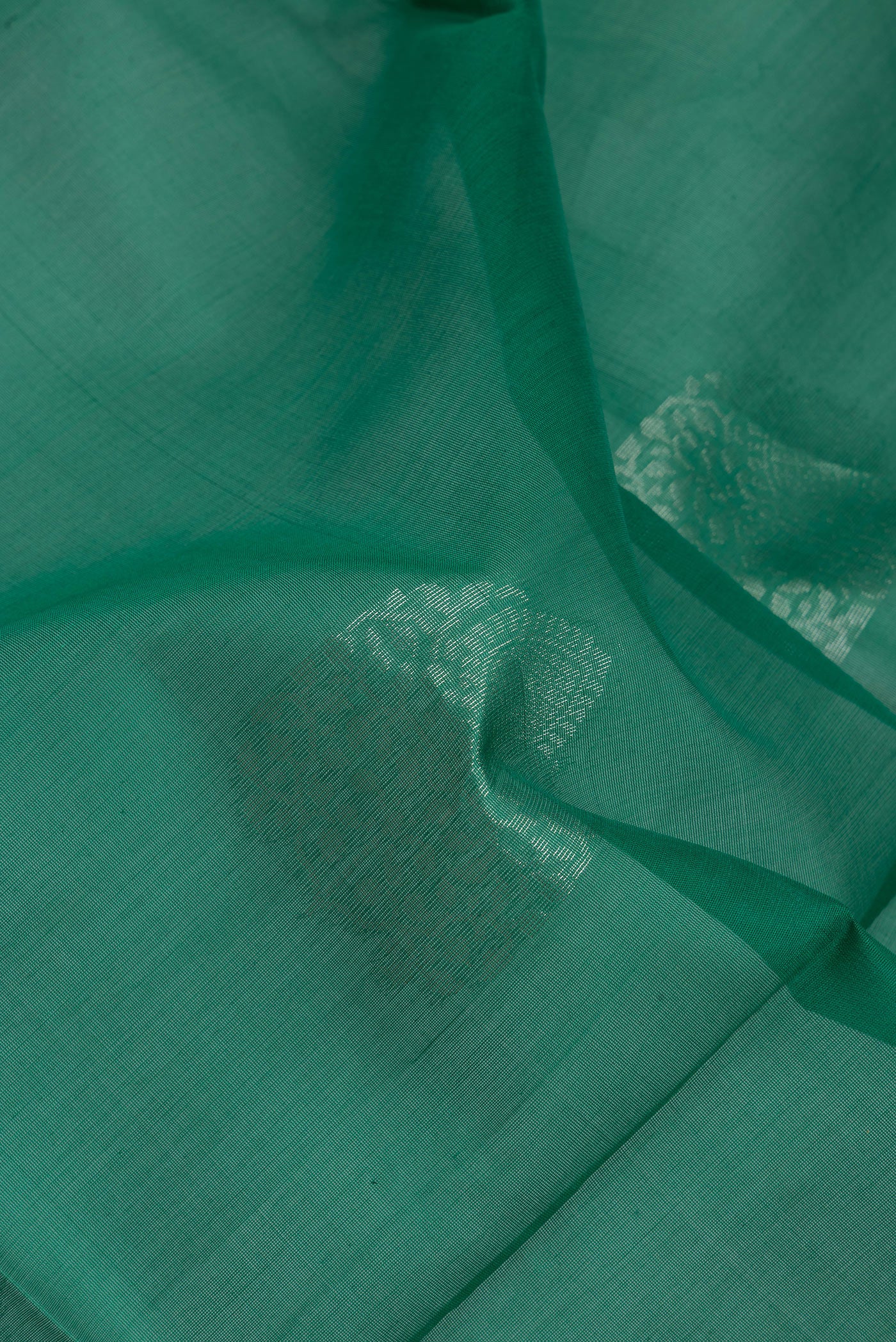 Close up of Bottle Green Silk Cotton Saree with Zari Butta on the body and Zari Border.  displaying folds