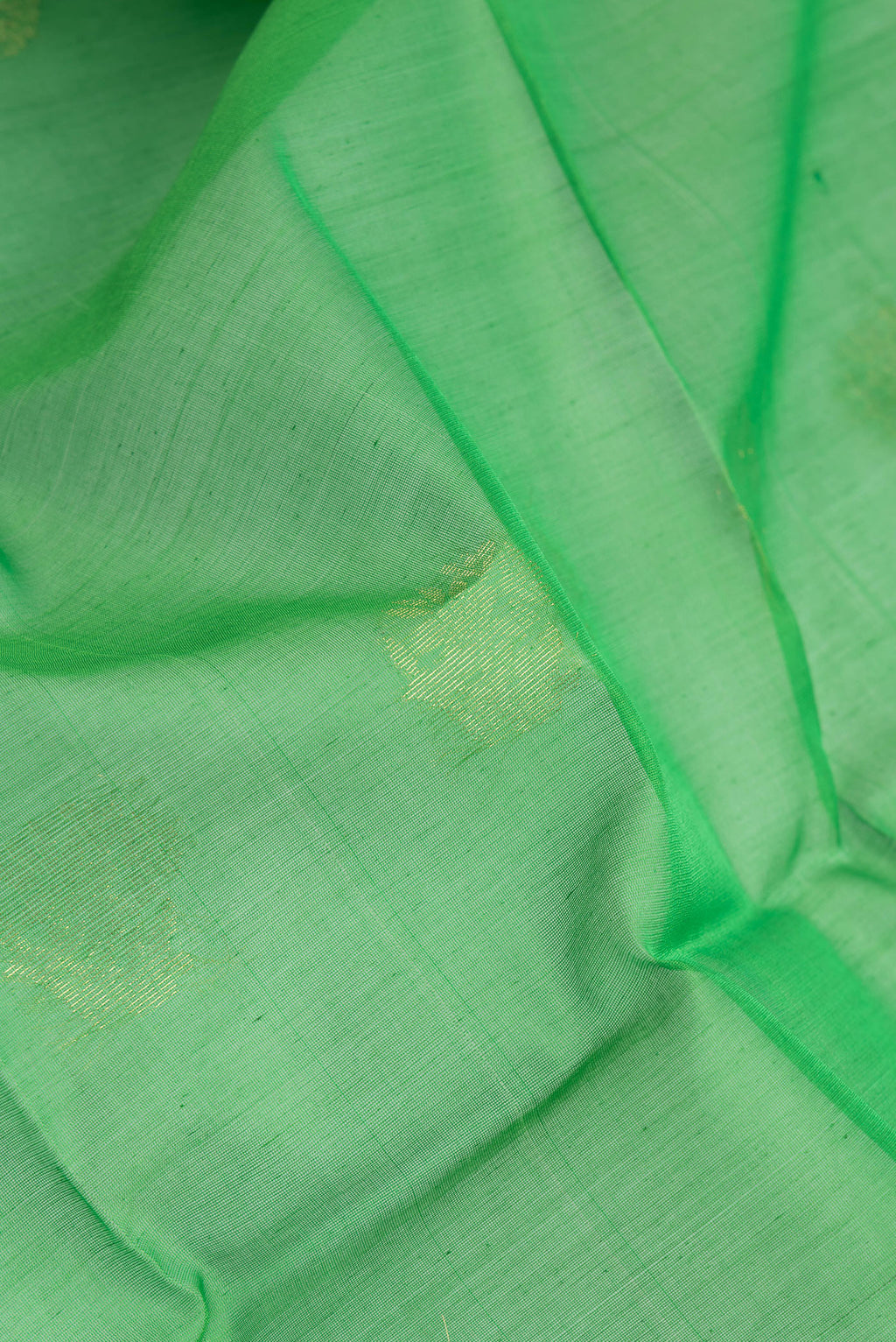 Close up of Green Silk Cotton Saree with Zari Butta on the body and Zari Border.  displaying folds