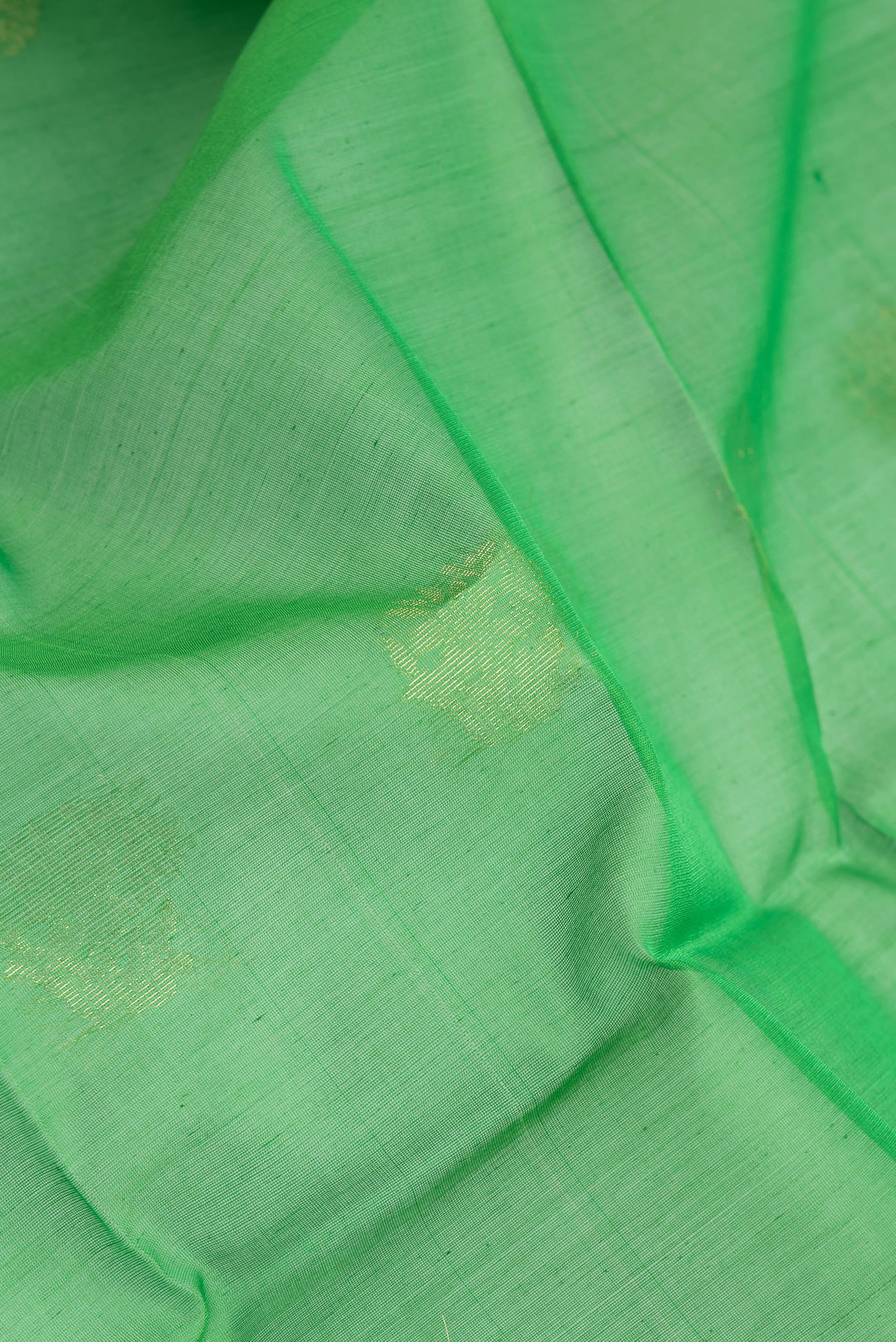 Close up of Green Silk Cotton Saree with Zari Butta on the body and Zari Border.  displaying folds