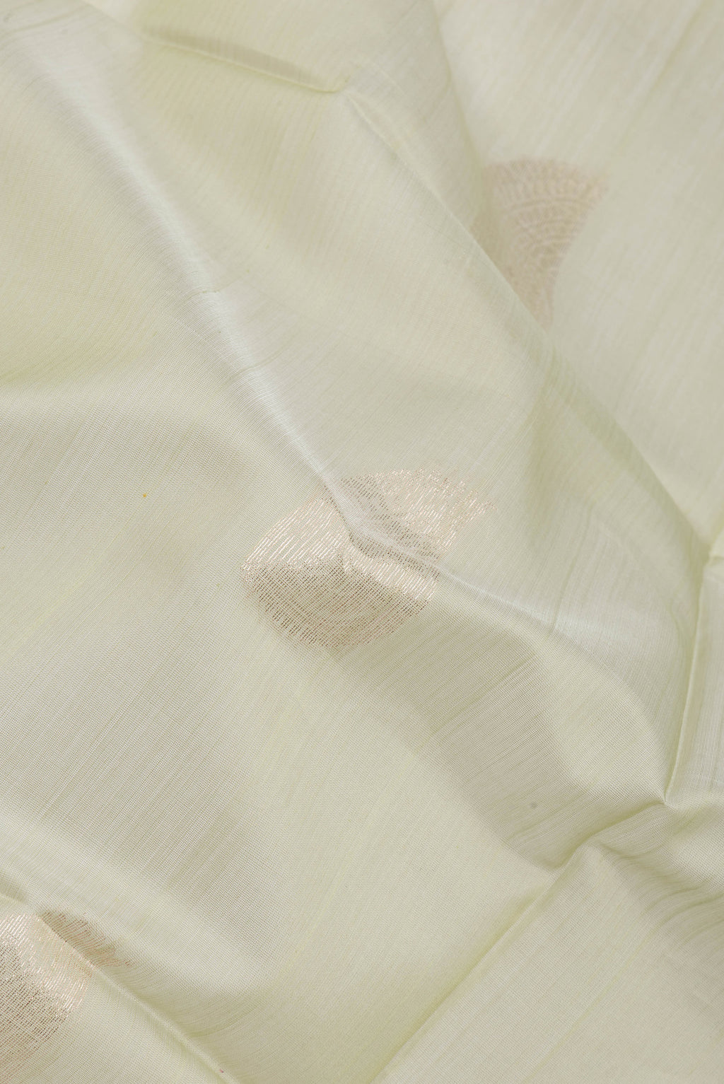 Close up of Pista Green Silk Cotton Saree with Zari Butta on the body and Zari Border.  displaying folds