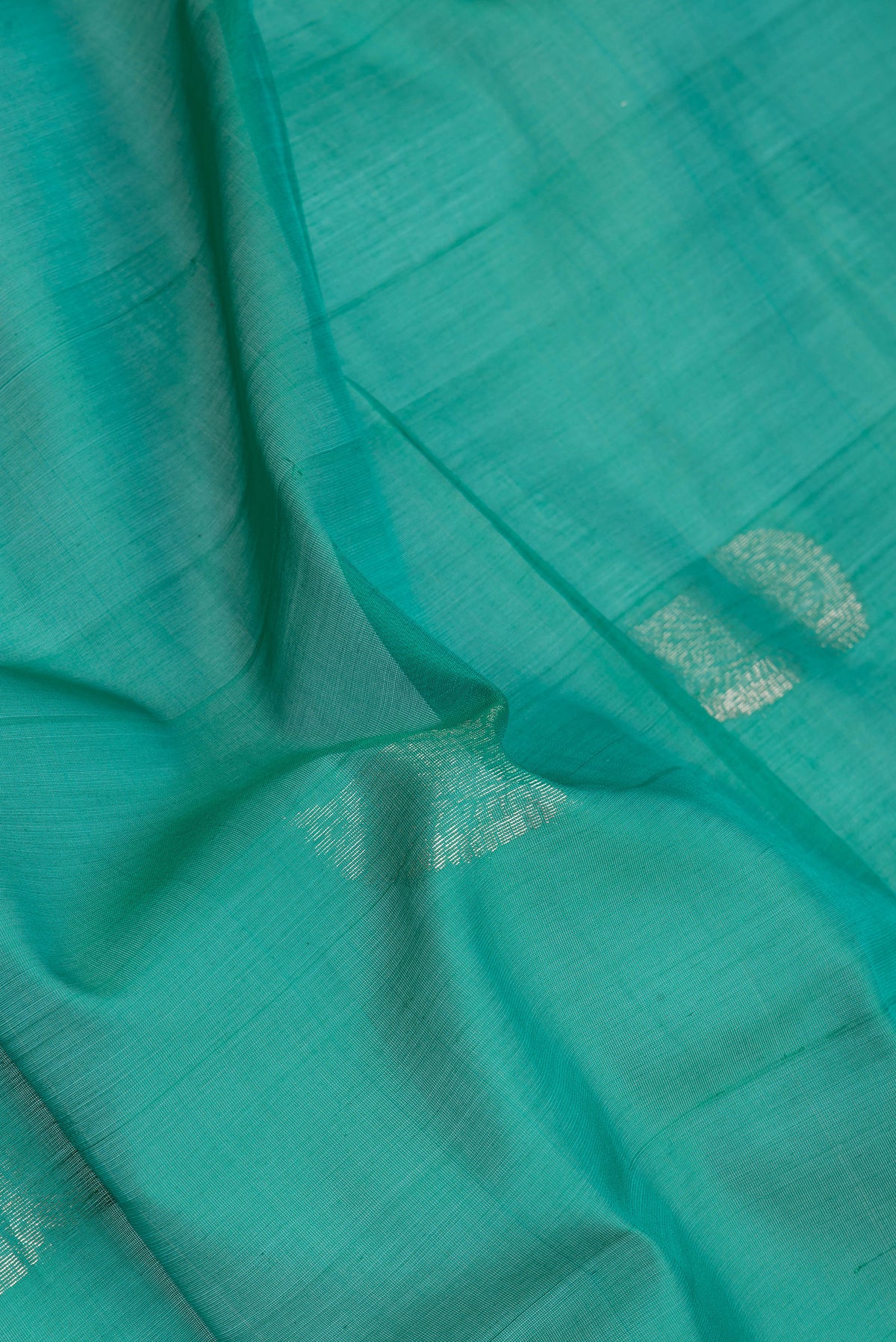 Close up of Green Silk Cotton Saree with Zari Butta on the body and Zari Border.  displaying folds