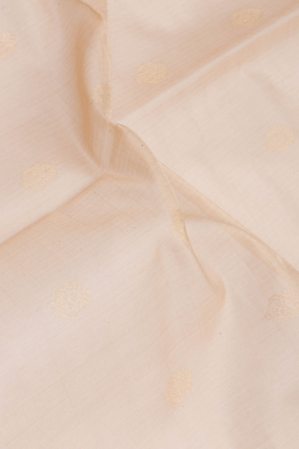 Close up of Beige Silk Cotton Saree with Zari Butta on the body and Zari Border.  displaying folds