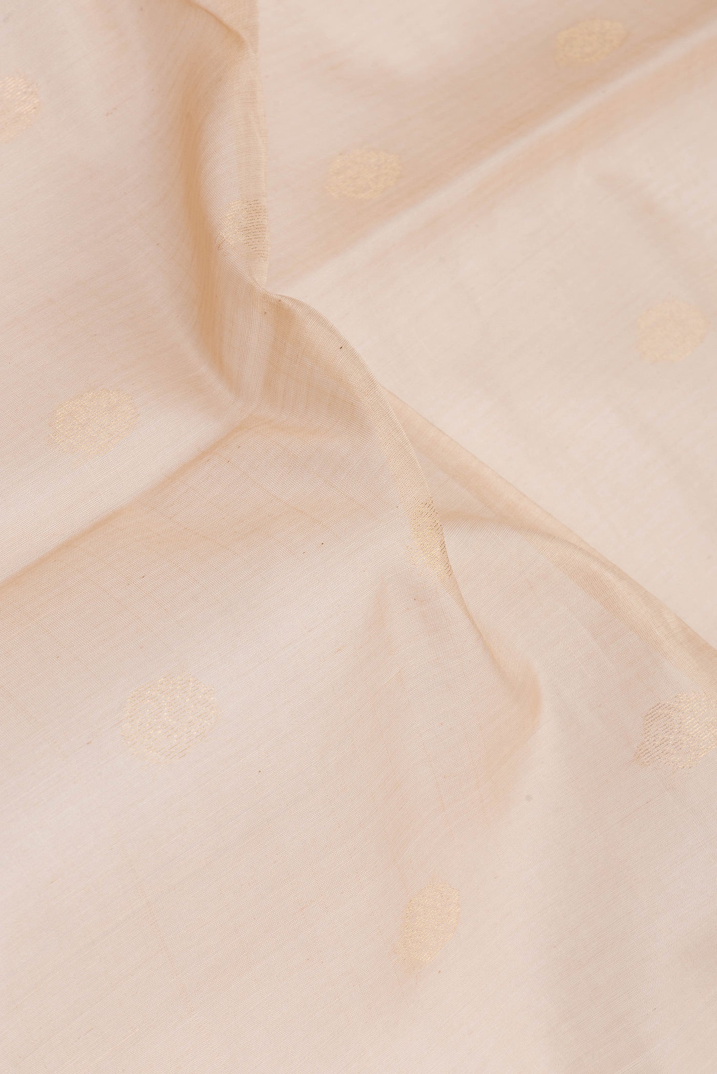 Close up of Beige Silk Cotton Saree with Zari Butta on the body and Zari Border.  displaying folds