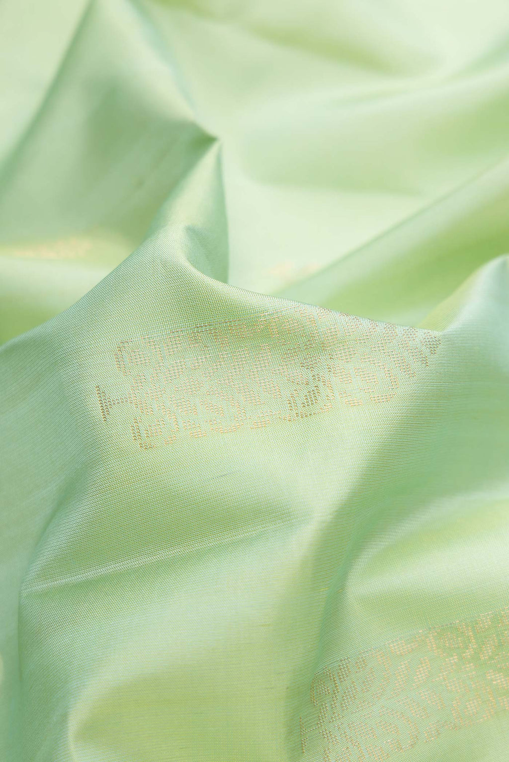 Close up of Pista Green Dual Tone Soft Silk Saree with Zari Butta on the body and Zari Border.  displaying folds