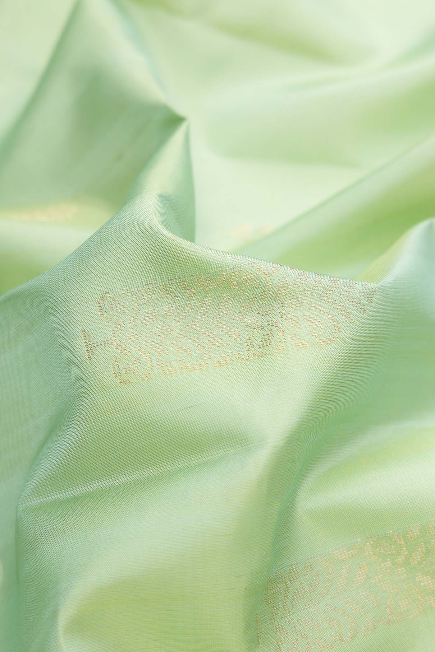 Close up of Pista Green Dual Tone Soft Silk Saree with Zari Butta on the body and Zari Border.  displaying folds