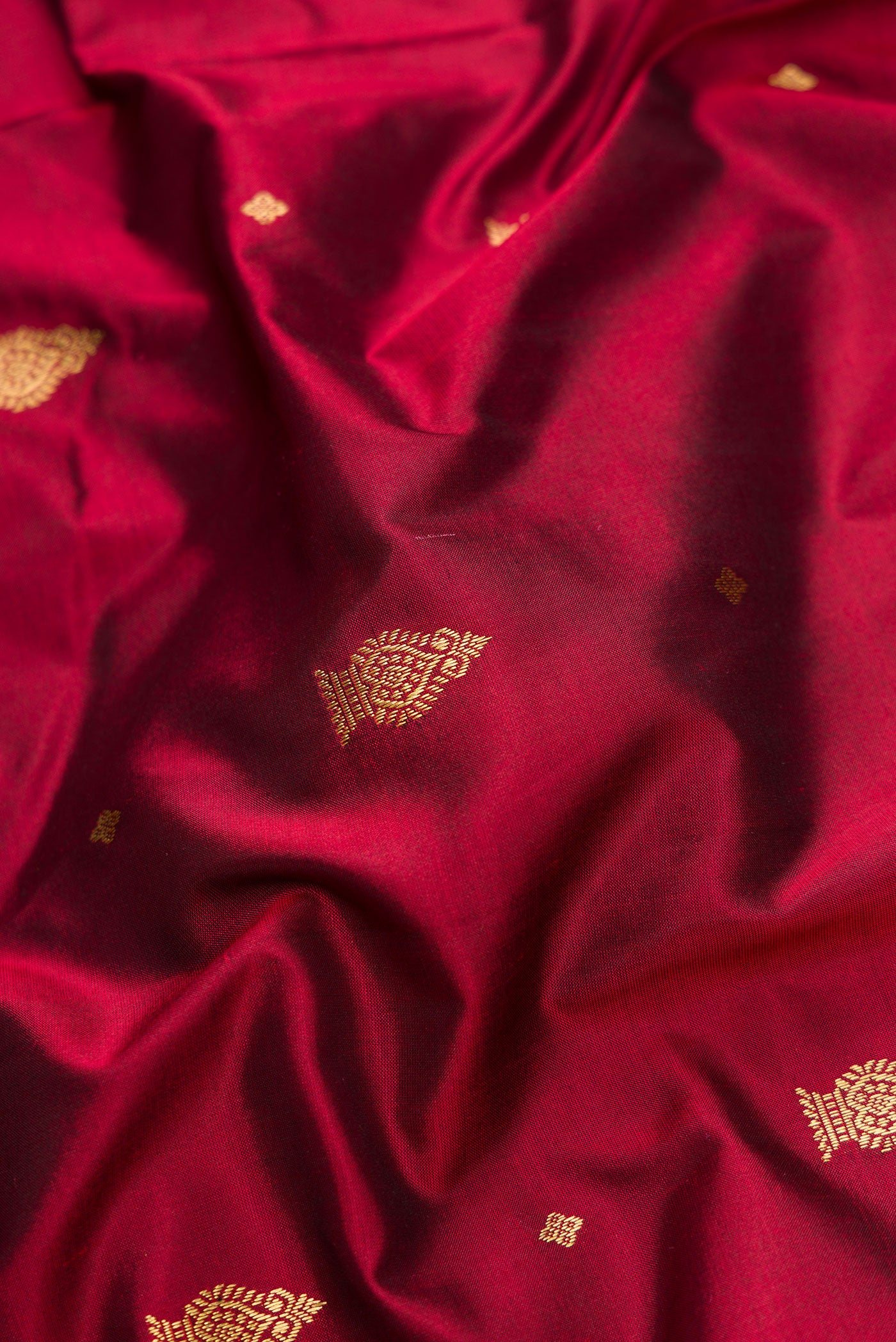 Close up of Maroon Dual Tone Kanchipuram Silk Saree with Zari Butta on the body and Temple Border.  displaying folds