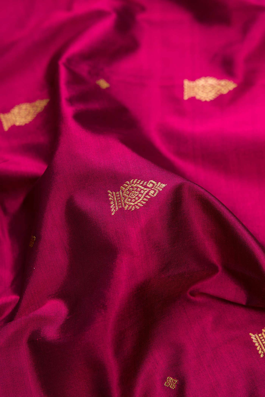 Close up of Magenta Dual Tone Kanchipuram Silk Saree with Zari Butta on the body and Temple Border.  displaying folds