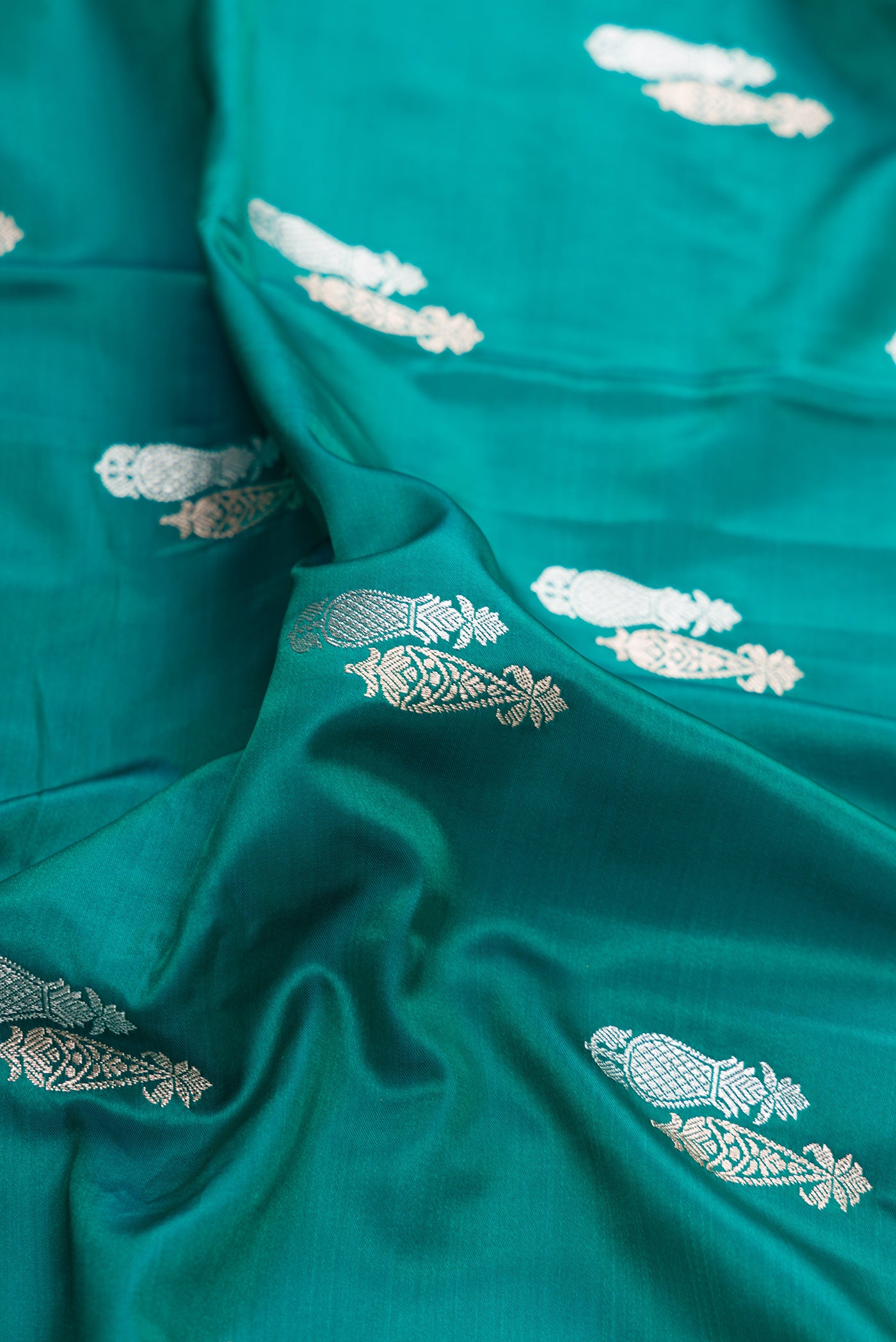 Close up of Green Dual Tone Banarasi Silk Saree with Zari Butta on the body and Zari Border.  displaying folds