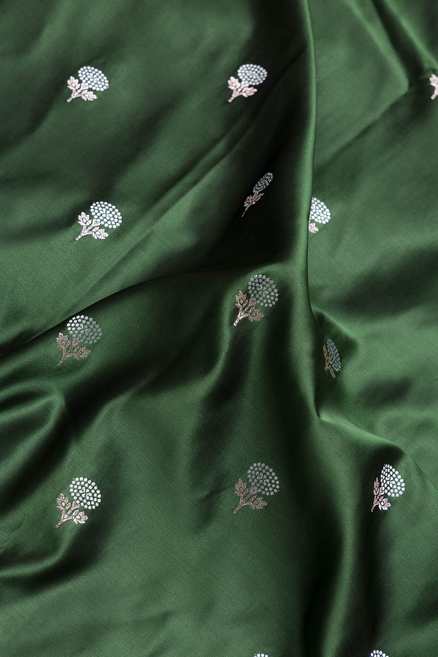 Close up of Bottle Green Dual Tone Banarasi Silk Saree with Zari Butta on the body and Zari Border.  displaying folds