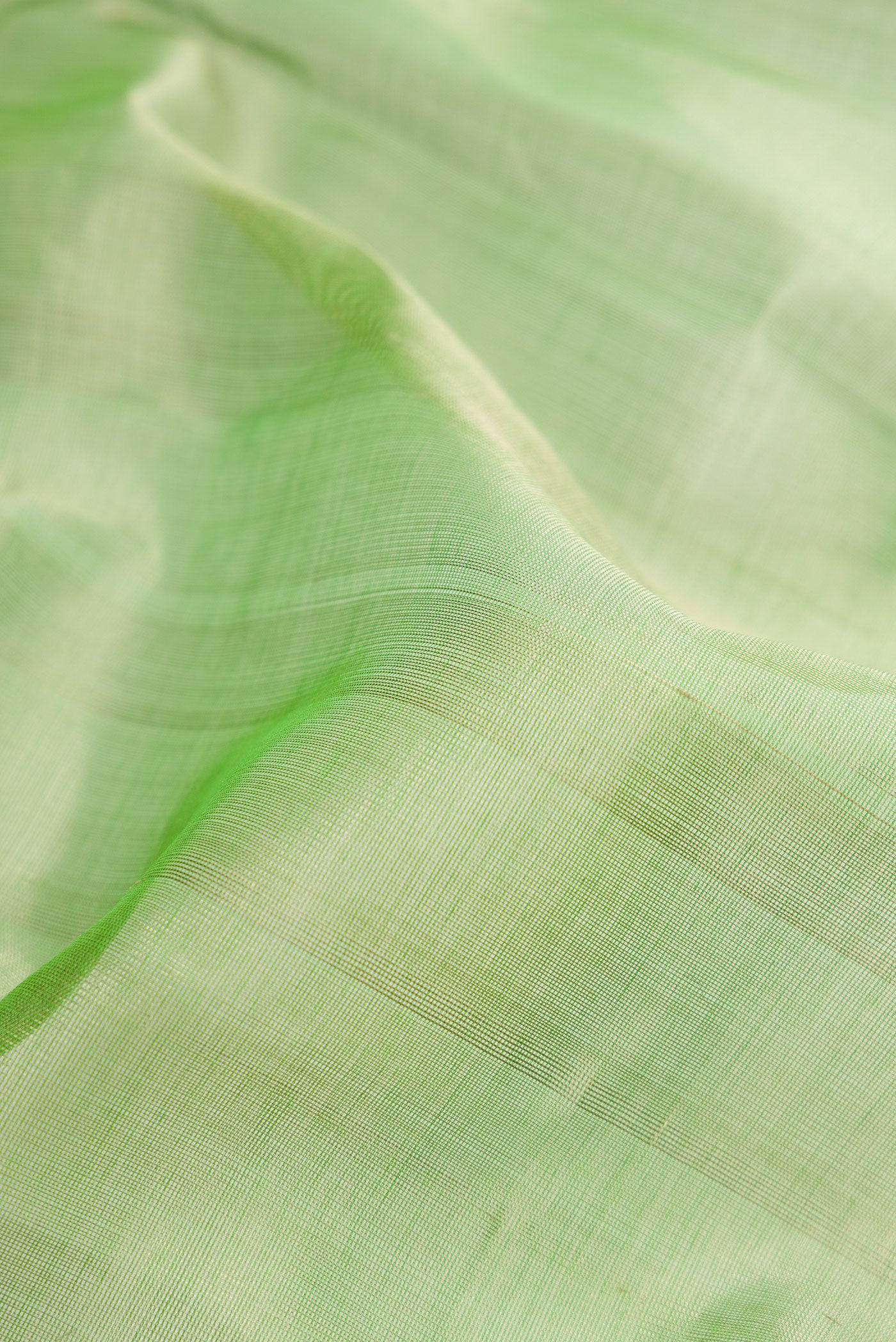 Close up of Light Green Silk Cotton Saree with Plain Body and Zari Border.  displaying folds