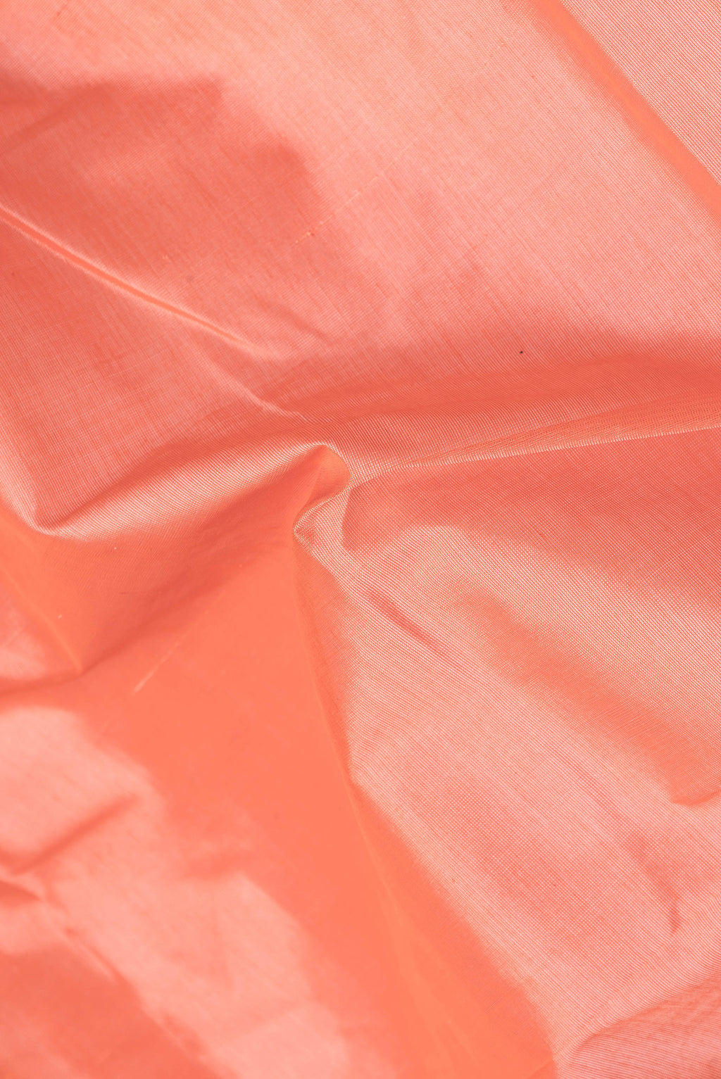 Close up of Coral Silk Cotton Saree with Plain Body and Zari Border.  displaying folds
