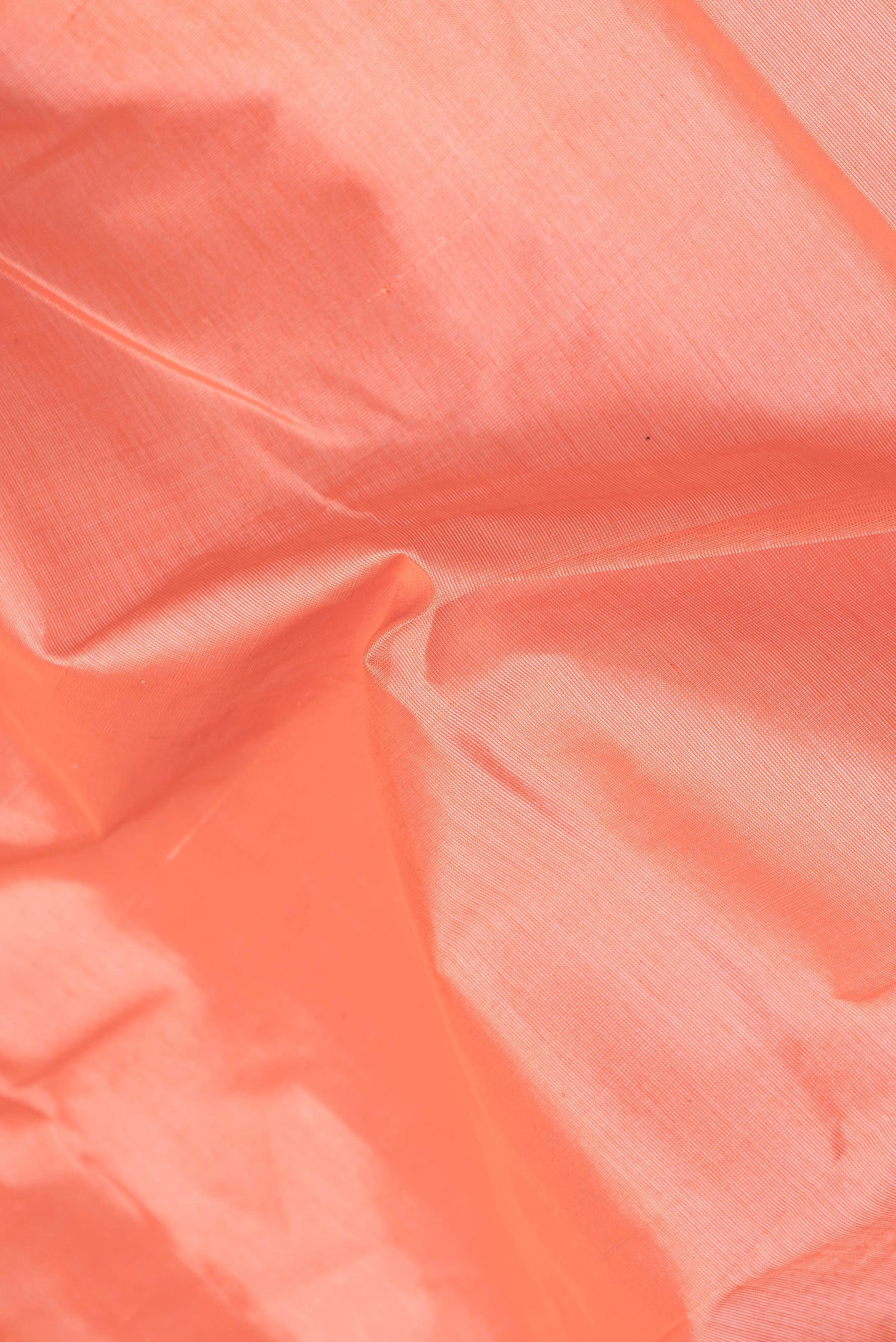 Close up of Coral Silk Cotton Saree with Plain Body and Zari Border.  displaying folds