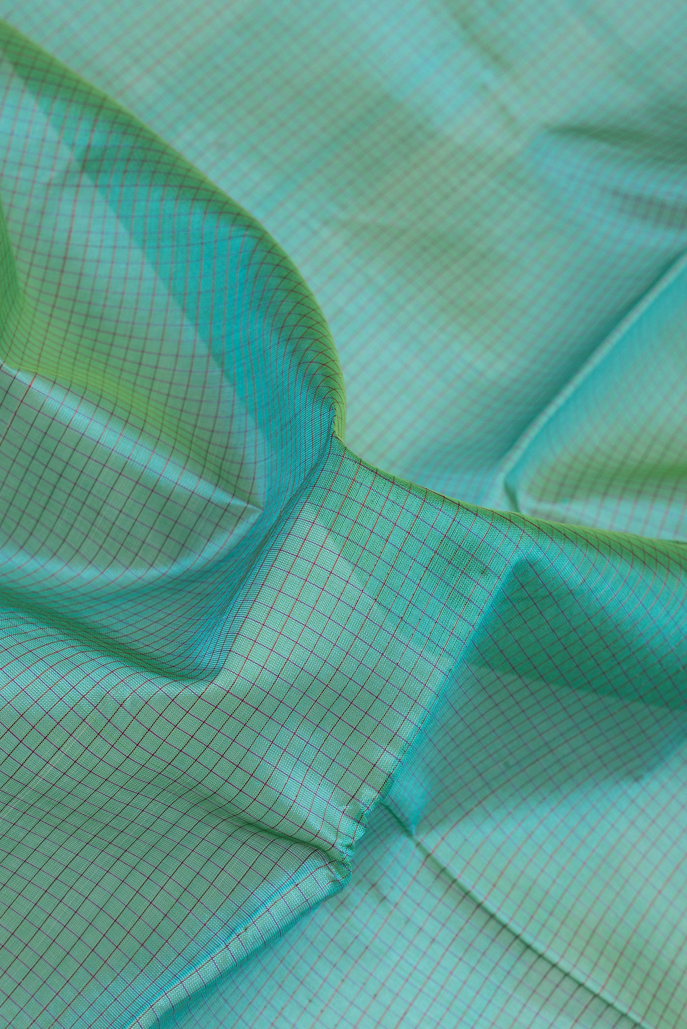 Close up of Peacock Blue Silk Cotton Saree with Checked design on the body and Zari Border.  displaying folds