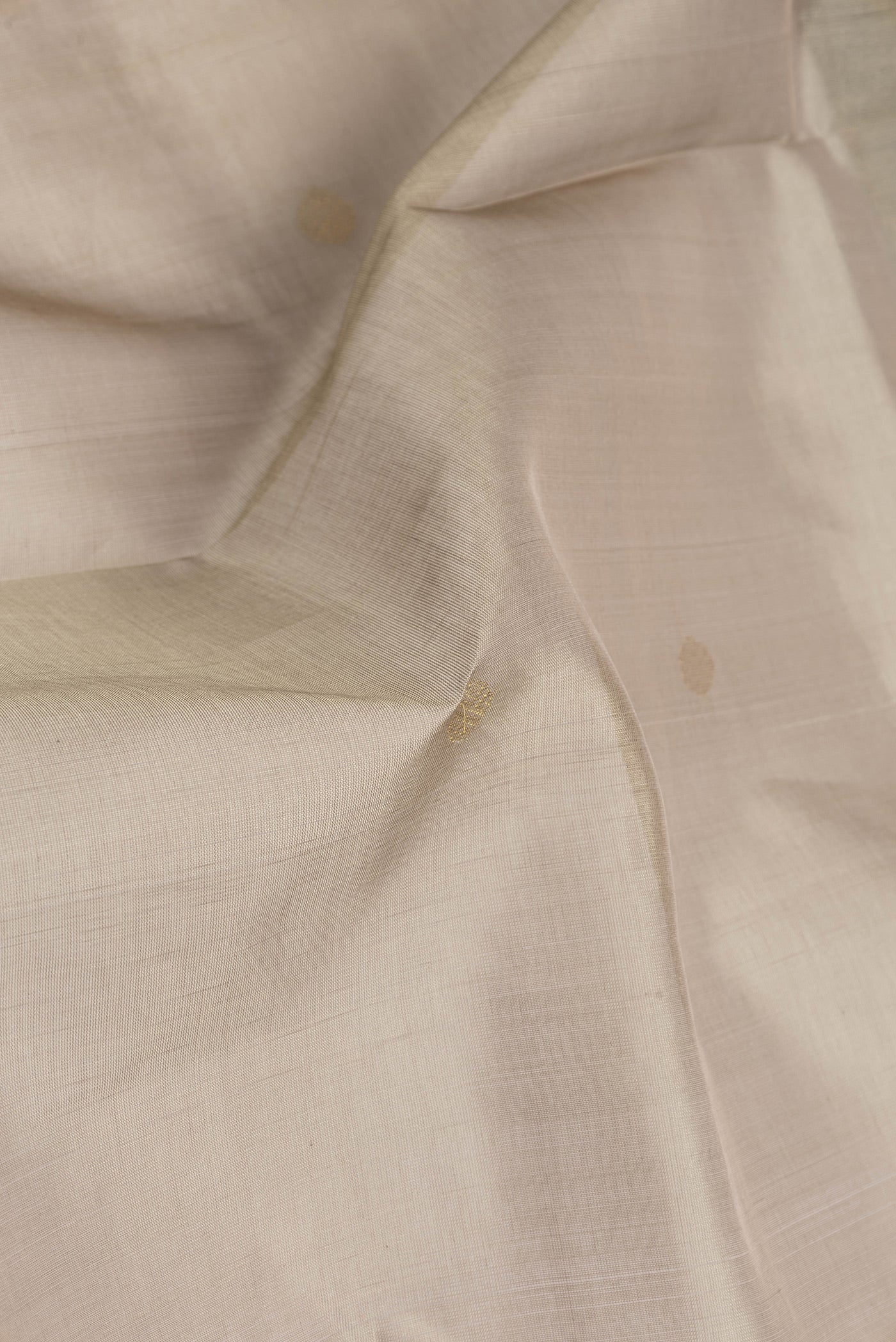Close up of Dark Beige Silk Cotton Saree with Zari Butta on the body and Zari Border.  displaying folds