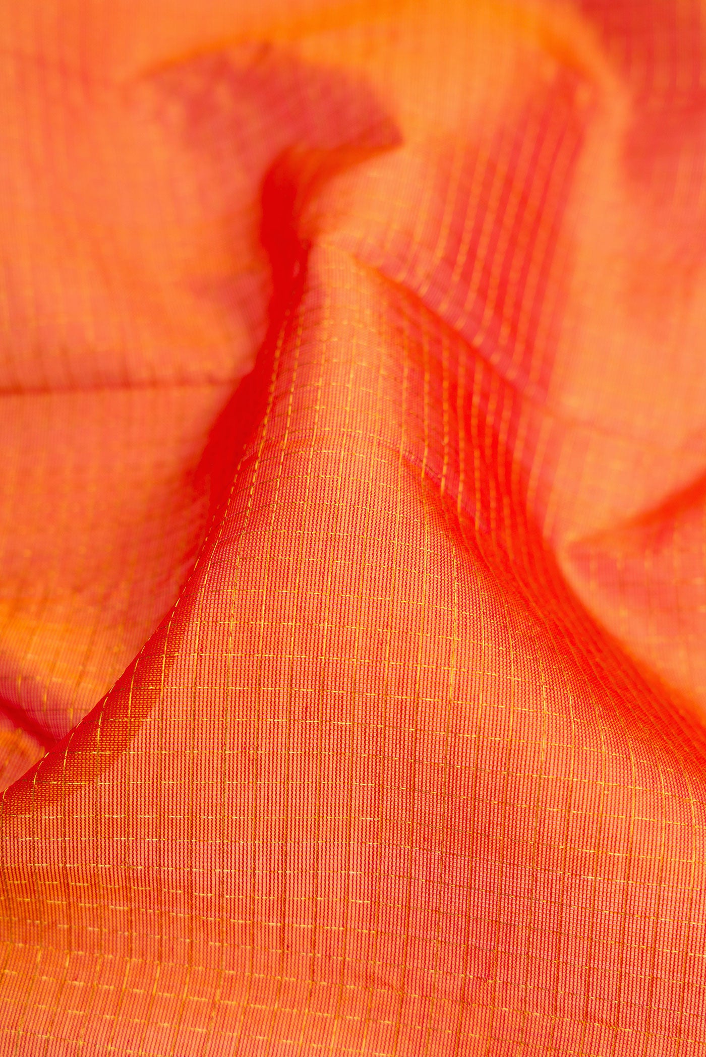 Close up of Orange Dual Tone Silk Cotton Saree with Checked design on the body and Zari Border.  displaying folds
