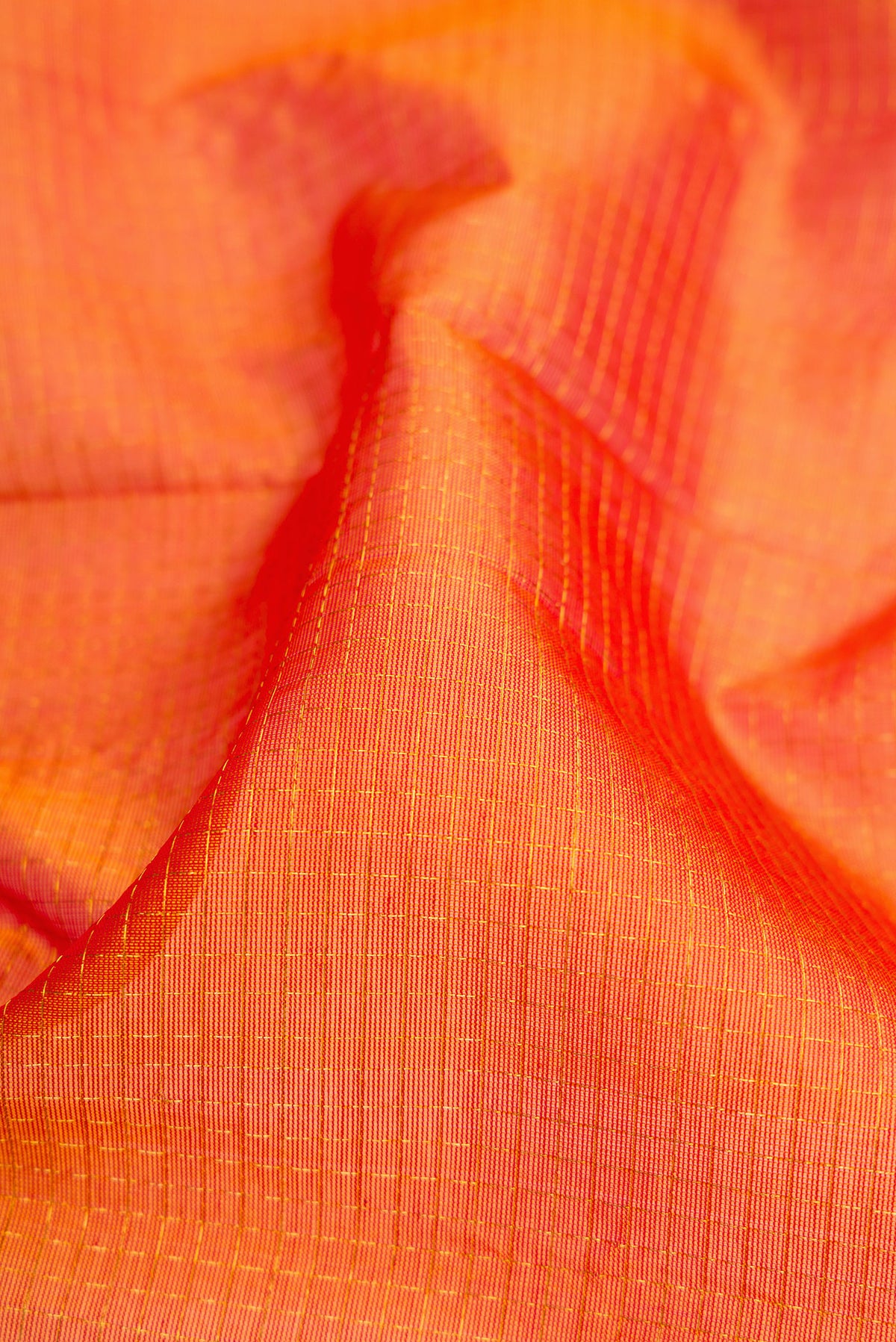 Close up of Orange Dual Tone Silk Cotton Saree with Checked design on the body and Zari Border.  displaying folds