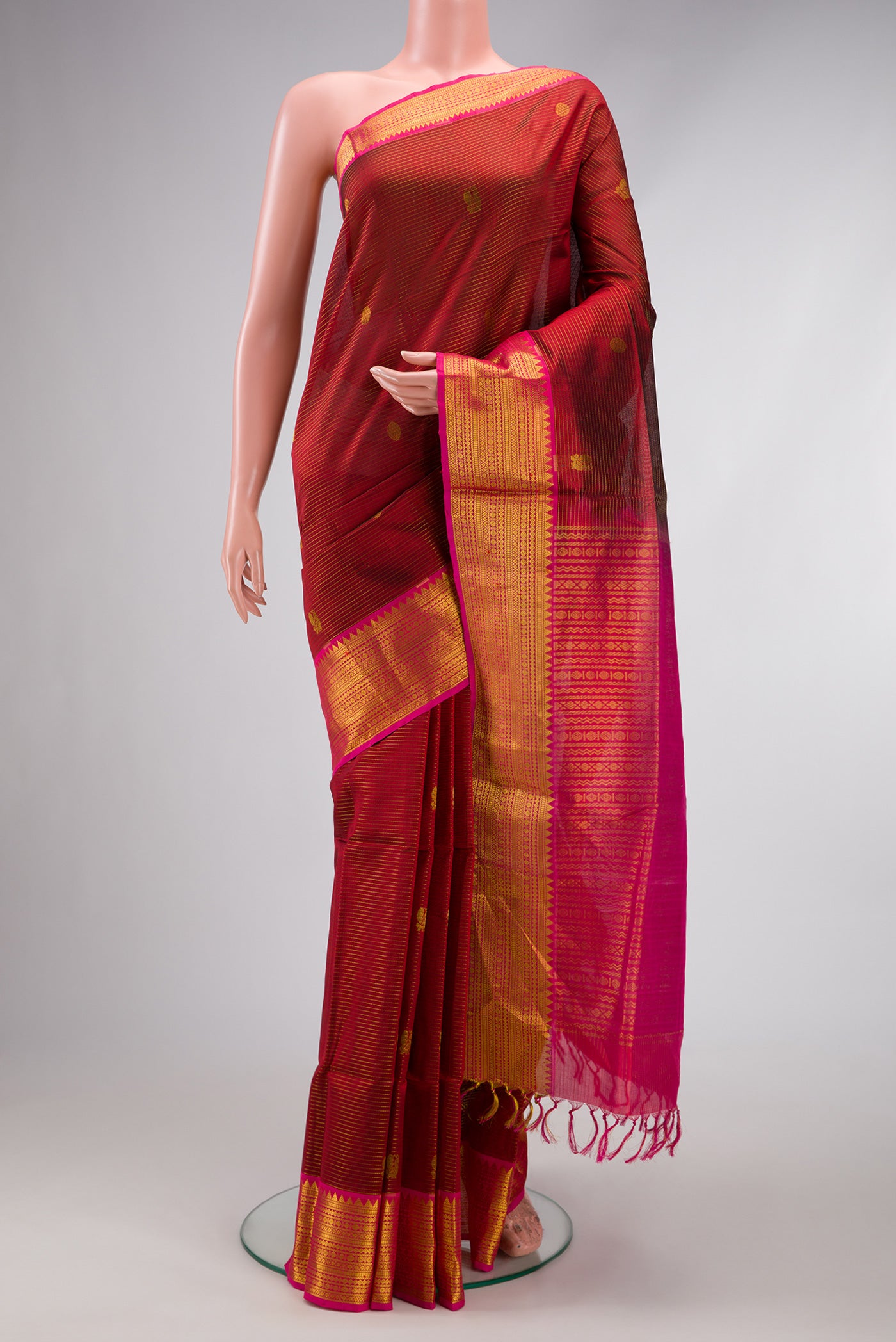 Maroon Silk Cotton Saree with Stripes on the body and Zari Border.  displayed on a mannequin