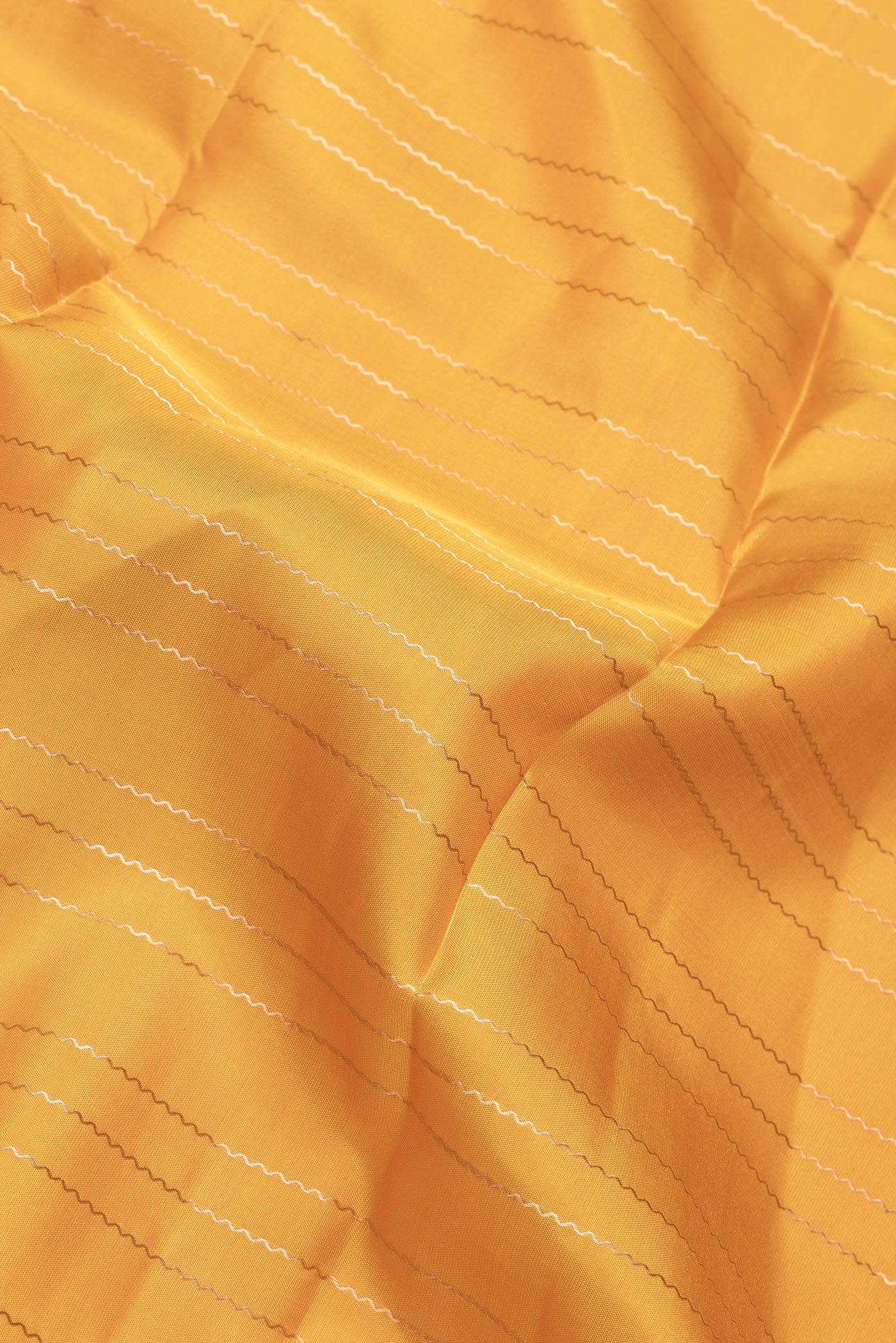 Close up of Mustard Dual Tone Kanchipuram Silk Saree with Stripes on the body and Zari Border.  displaying folds
