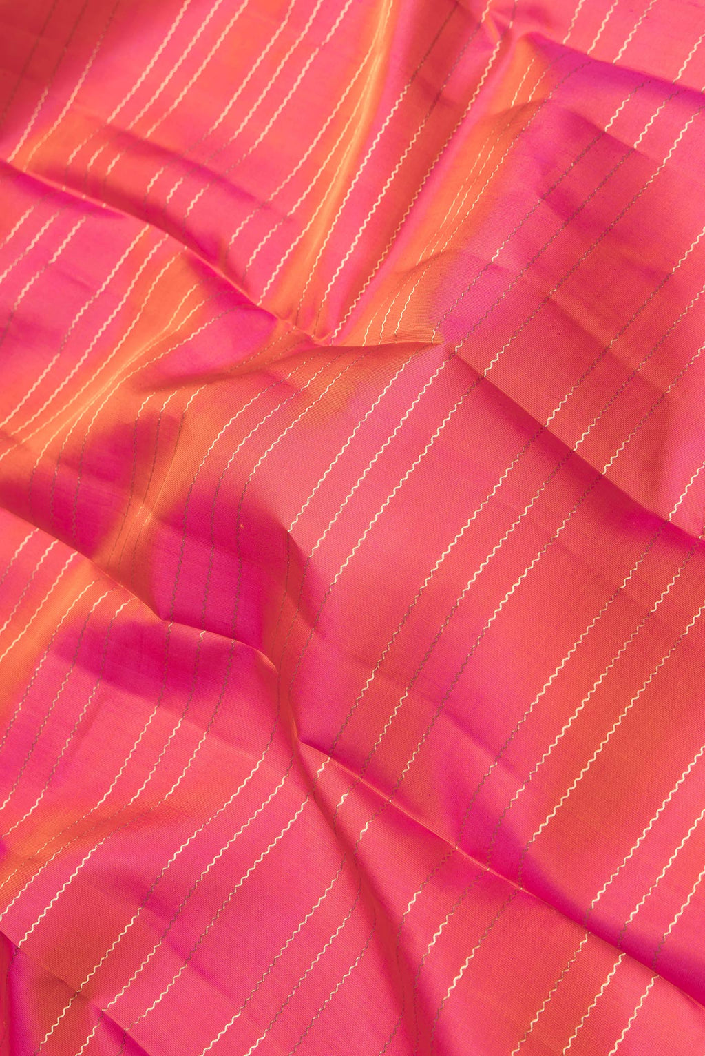 Close up of Orange Dual Tone Kanchipuram Silk Saree with Stripes on the body and Zari Border.  displaying folds