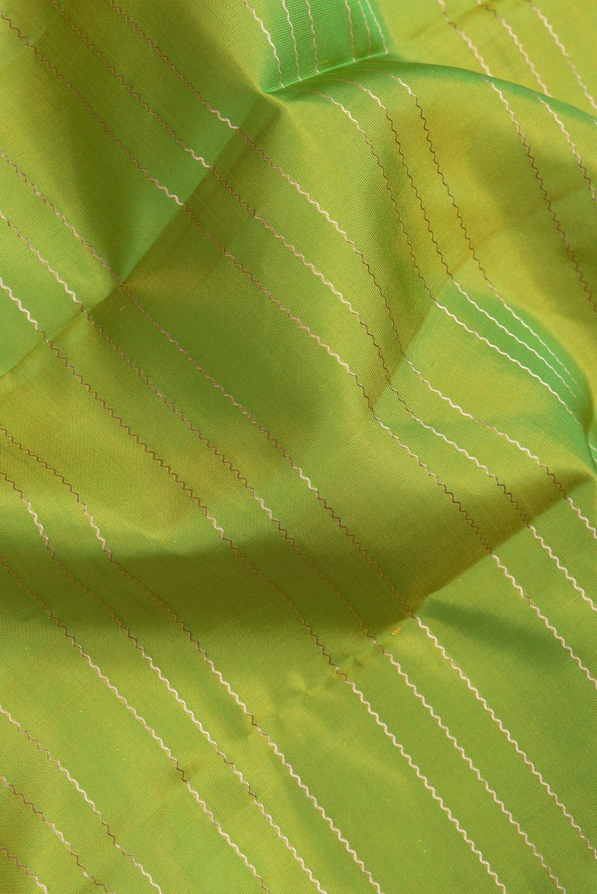 Close up of Parrot Green Dual Tone Kanchipuram Silk Saree with Stripes on the body and Zari Border.  displaying folds
