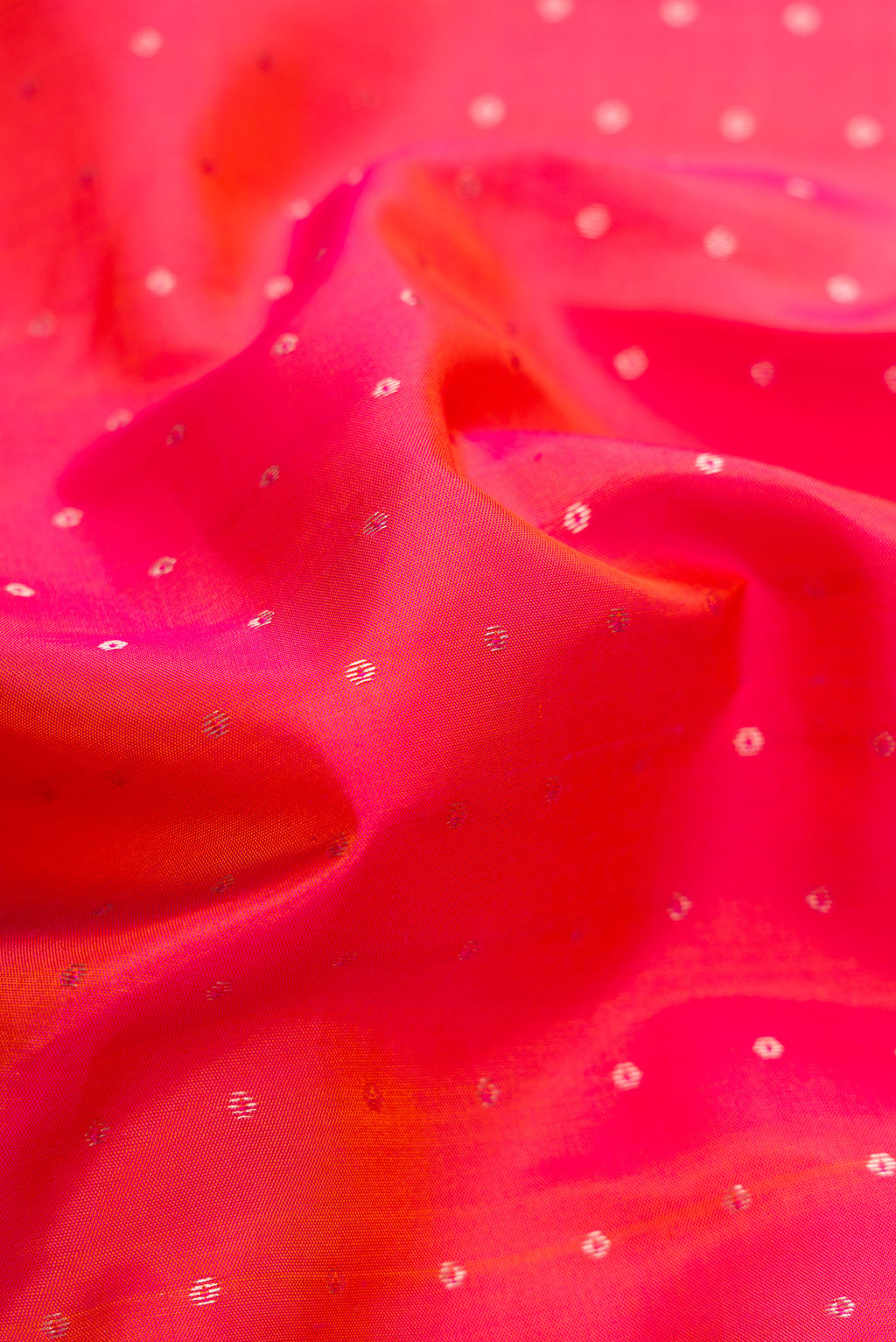 Close up of Coral Dual Tone Kanchipuram Silk Saree with Zari Butta on the body and Zari Border.  displaying folds