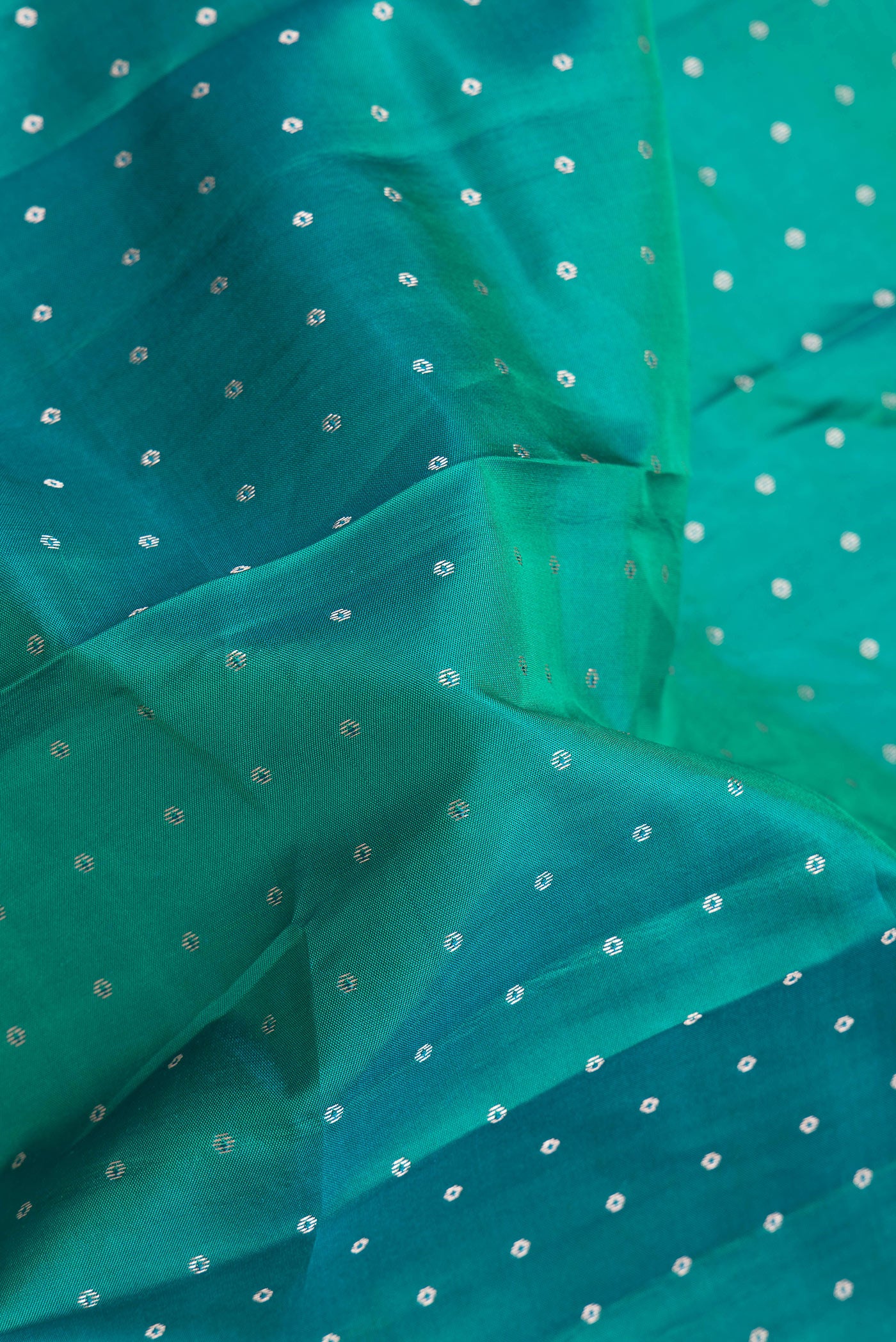 Close up of Green Dual Tone Kanchipuram Silk Saree with Zari Butta on the body and Zari Border.  displaying folds