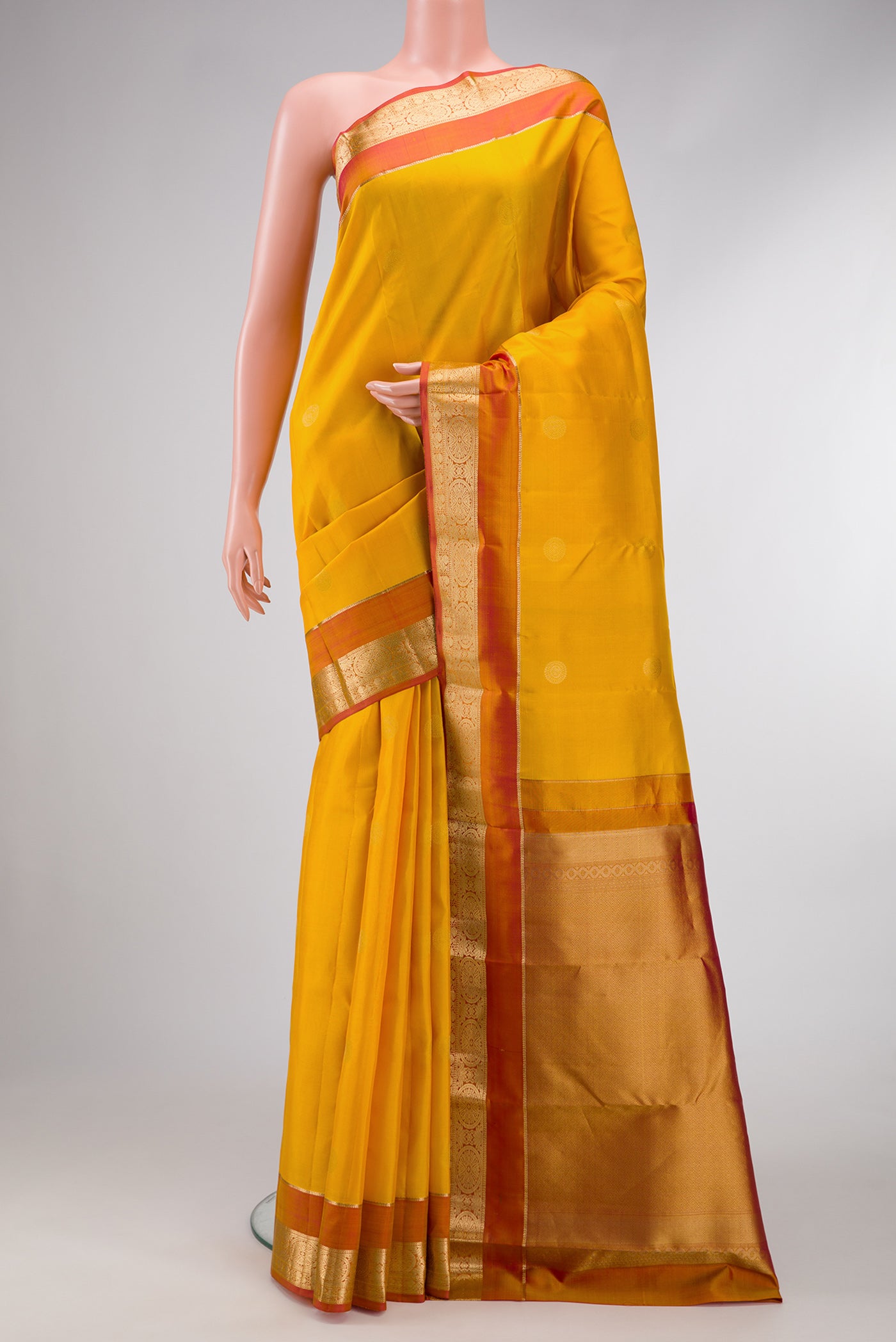 Mustard Dual Tone Kanchipuram Silk Saree with Zari Butta on the body and Zari Border.  displayed on a mannequin