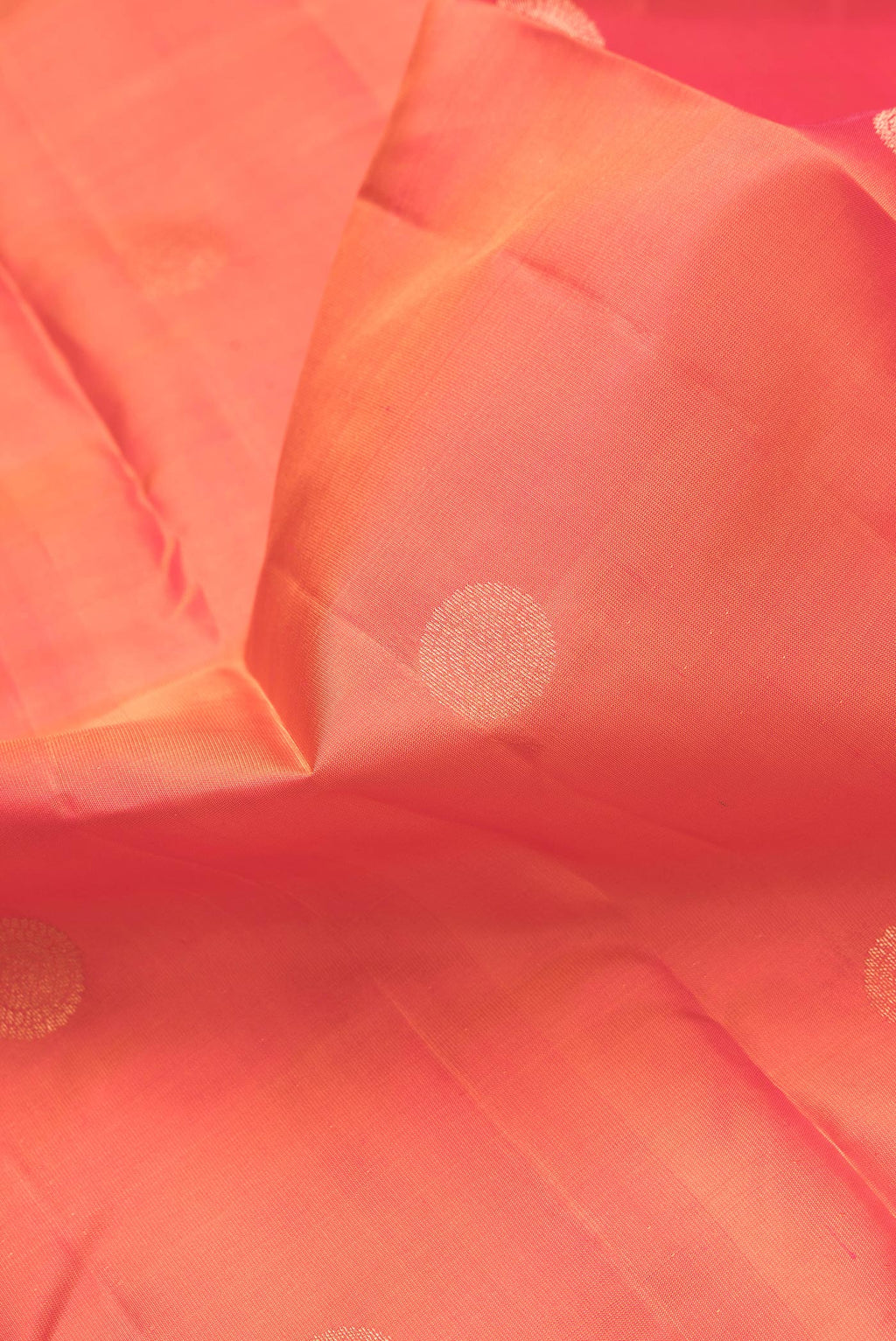 Close up of Orange Dual Tone Kanchipuram Silk Saree with Zari Butta on the body and Zari Border.  displaying folds