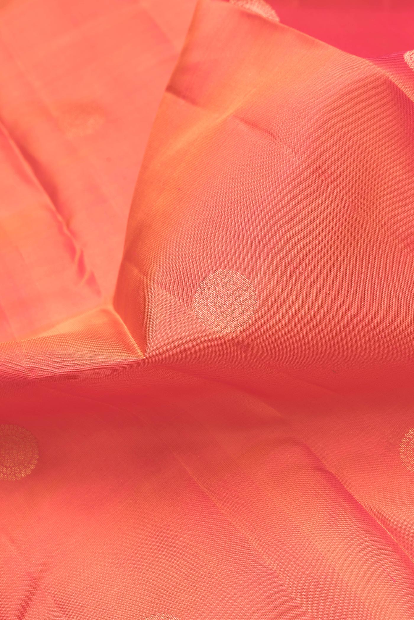 Close up of Orange Dual Tone Kanchipuram Silk Saree with Zari Butta on the body and Zari Border.  displaying folds